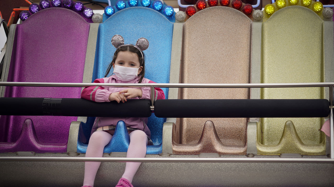 A young girl wearing a face mask rides a fairground attrtction on the Central Pier on October 16, 2020 in Blackpool, England. The Lancashire region will go into Tier 3 of Covid-19 lockdown restrictions from 00.01 Saturday 17th October. 