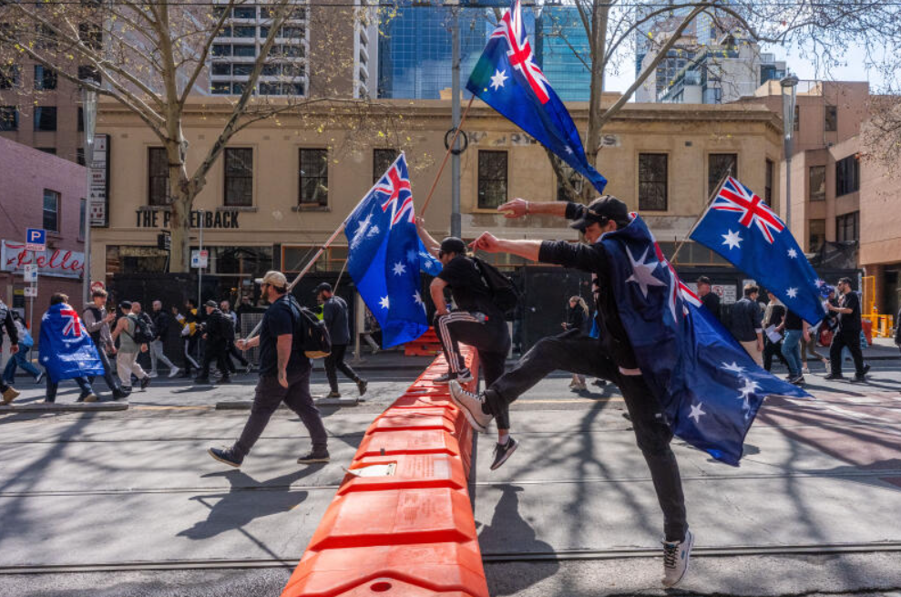 Anti-Government protesters leap of a road block as they march on September 13, 2025 in Melbourne, Australia. Australians rallied in multiple cities on the weekend in a call for unity after right-wing protesters staged marches through Australian CBDs last week