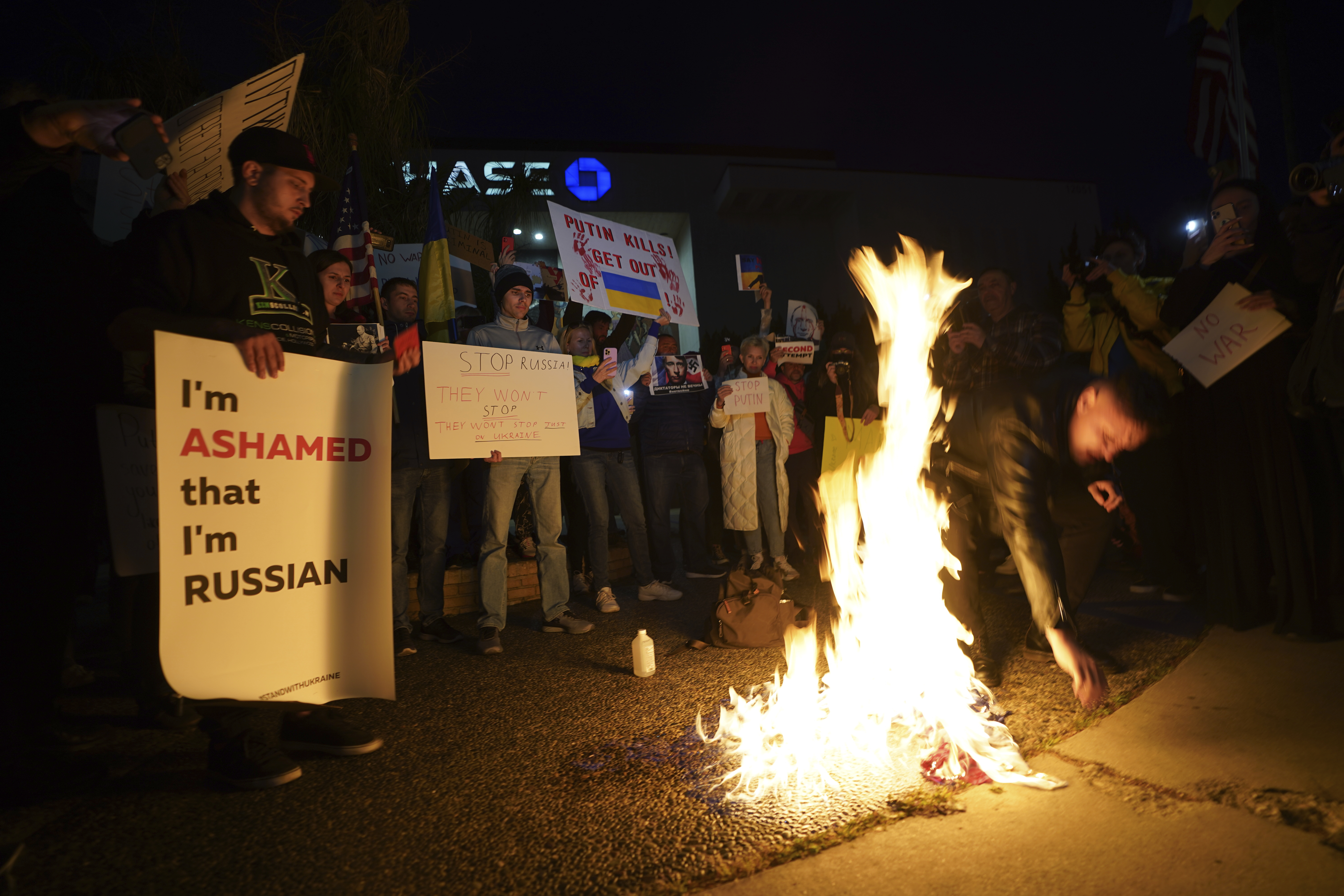 A Russian citizen burns a Russian flag as people protest the Russian invasion of Ukraine at a demonstration in the Studio City neighbourhood of Los Angeles, Thursday, Feb. 24, 2022