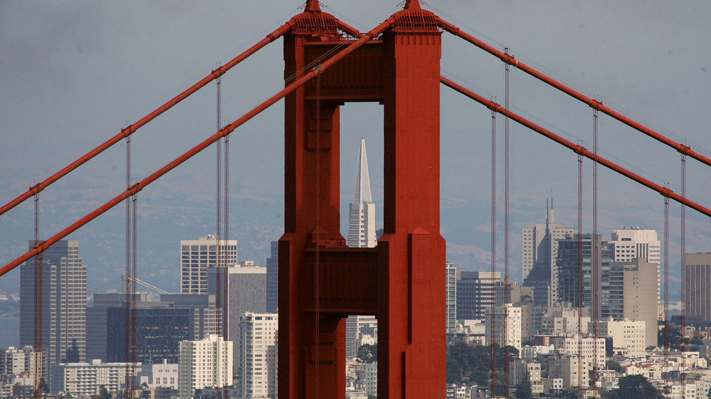 The Transamerica Pyramid building is seen through the north tower of the Golden Gate Bridge
