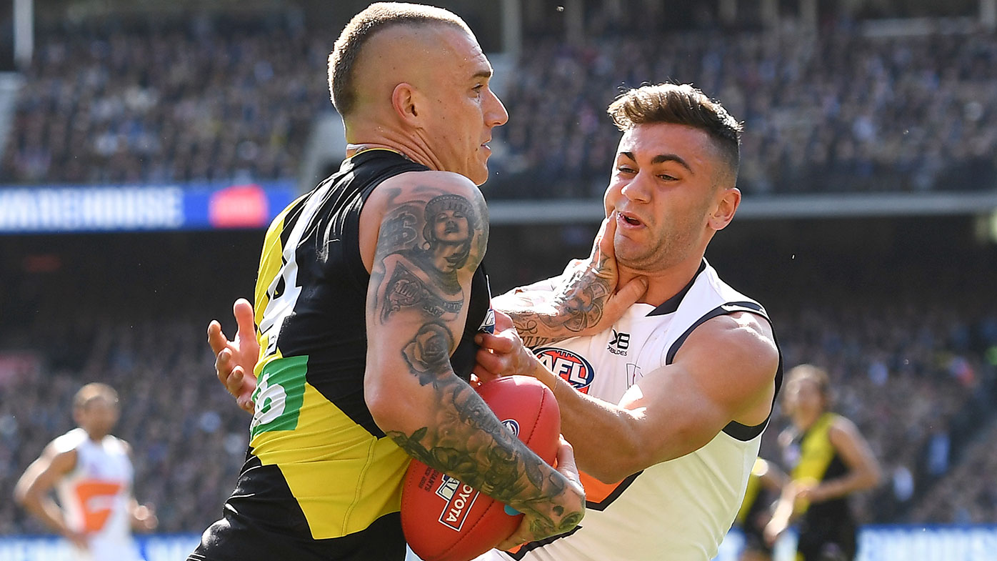 Dustin Martin of the Tigers fends off a tackle by Tim Taranto of the Giants