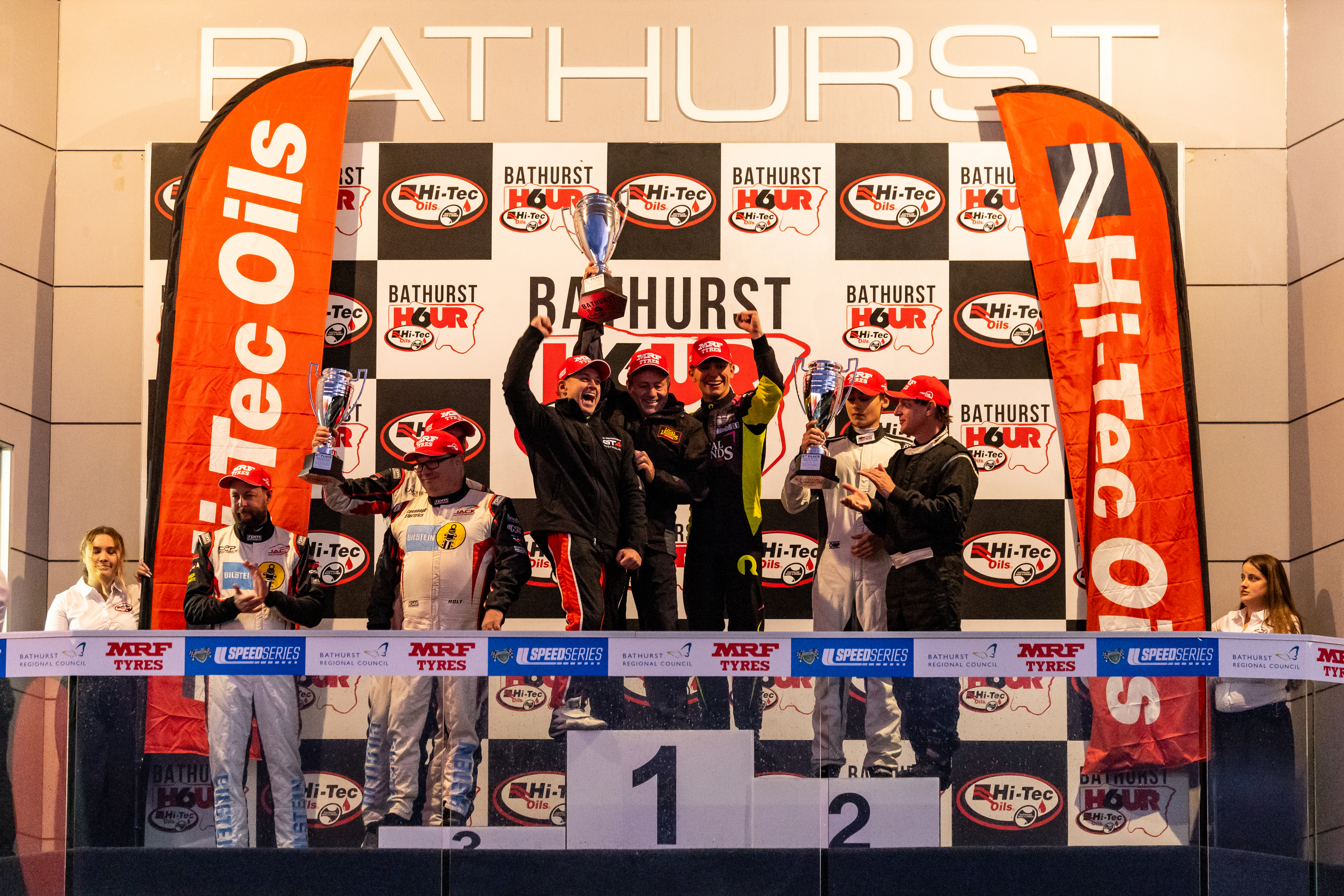 Grant Denyer, Tony Quinn, and Ryder Quinn stand on top of the Bathurst 6 Hour podium.