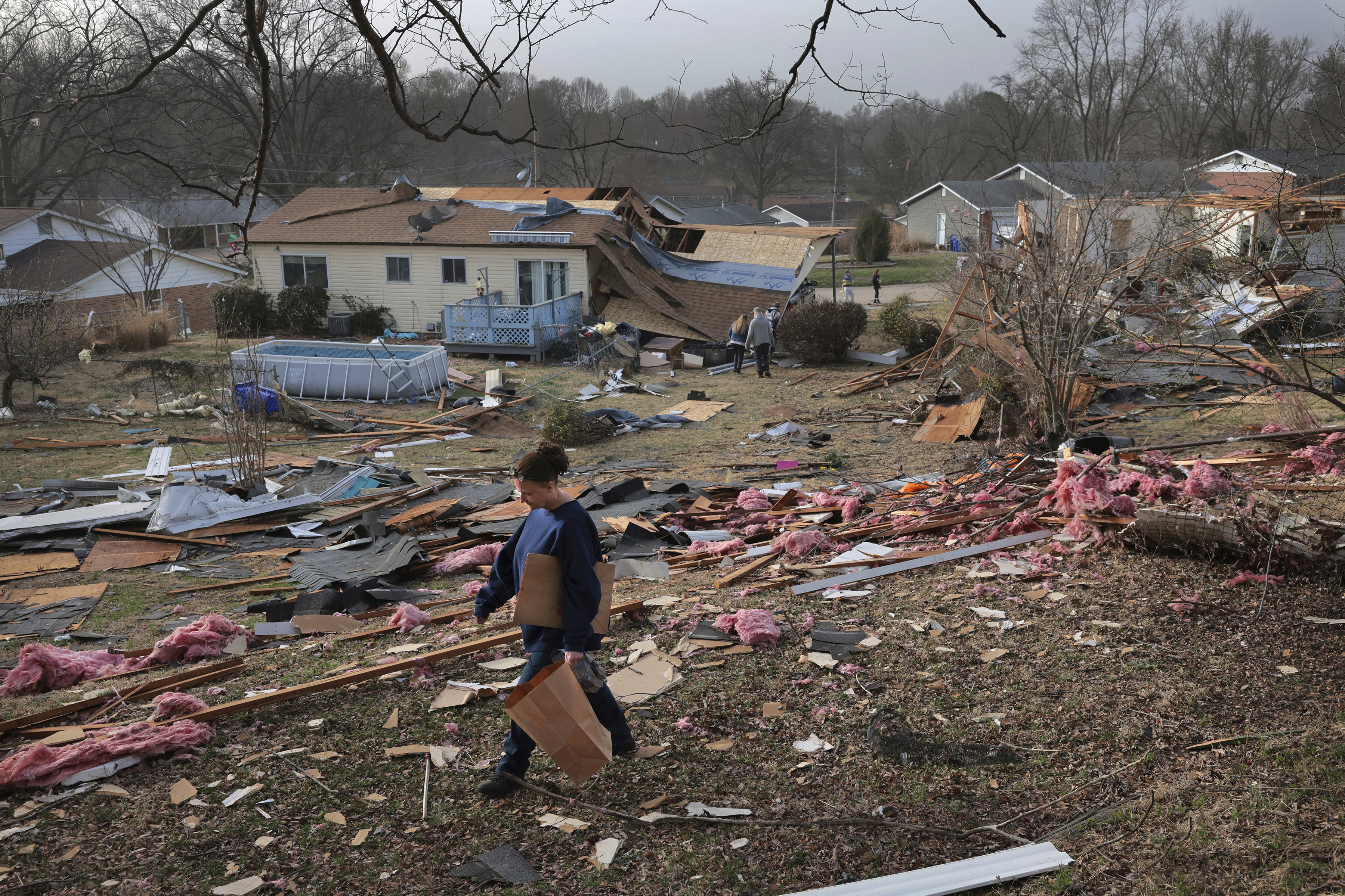 Missy, who declined to give her last name, searches for photographs in a debris field behind a relative's home after a severe storm