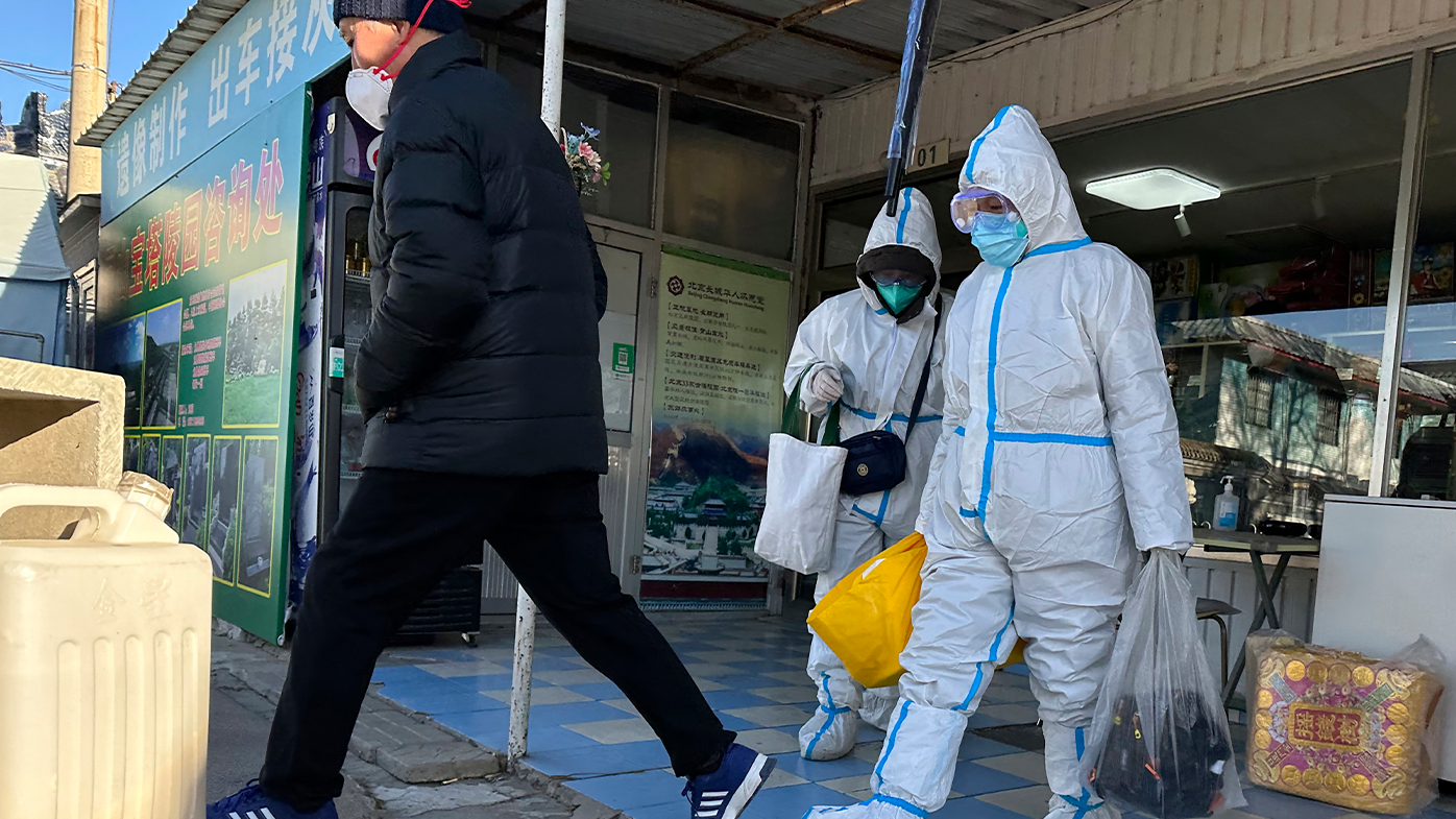 Miembros de la familia con equipo de protección recogen los restos cremados de su ser querido envueltos en un paño amarillo en un crematorio en Beijing, el sábado 17 de diciembre de 2022. 