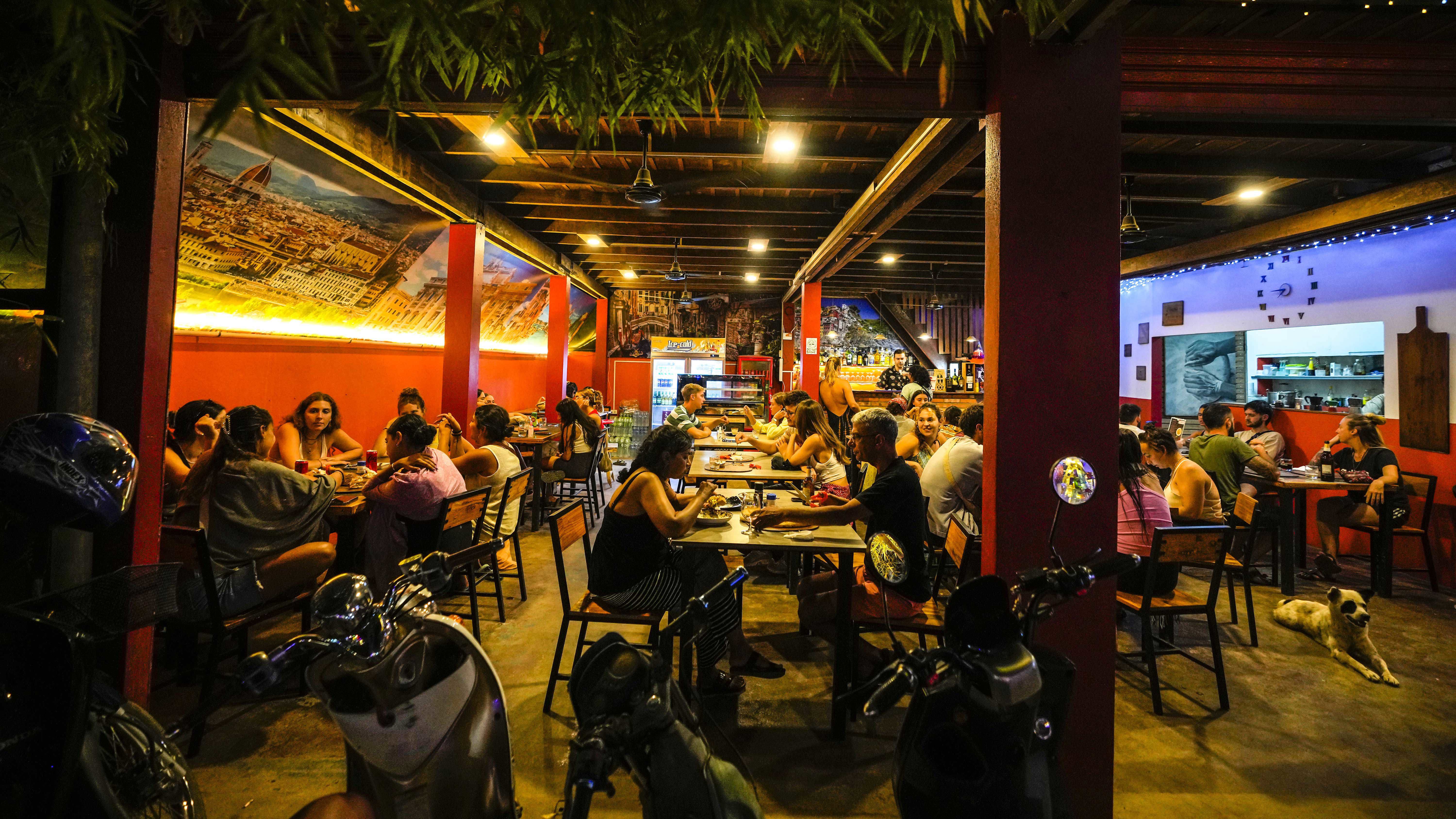 Tourists have drinks and pizza at a restaurant in Vang Vieng, Laos.