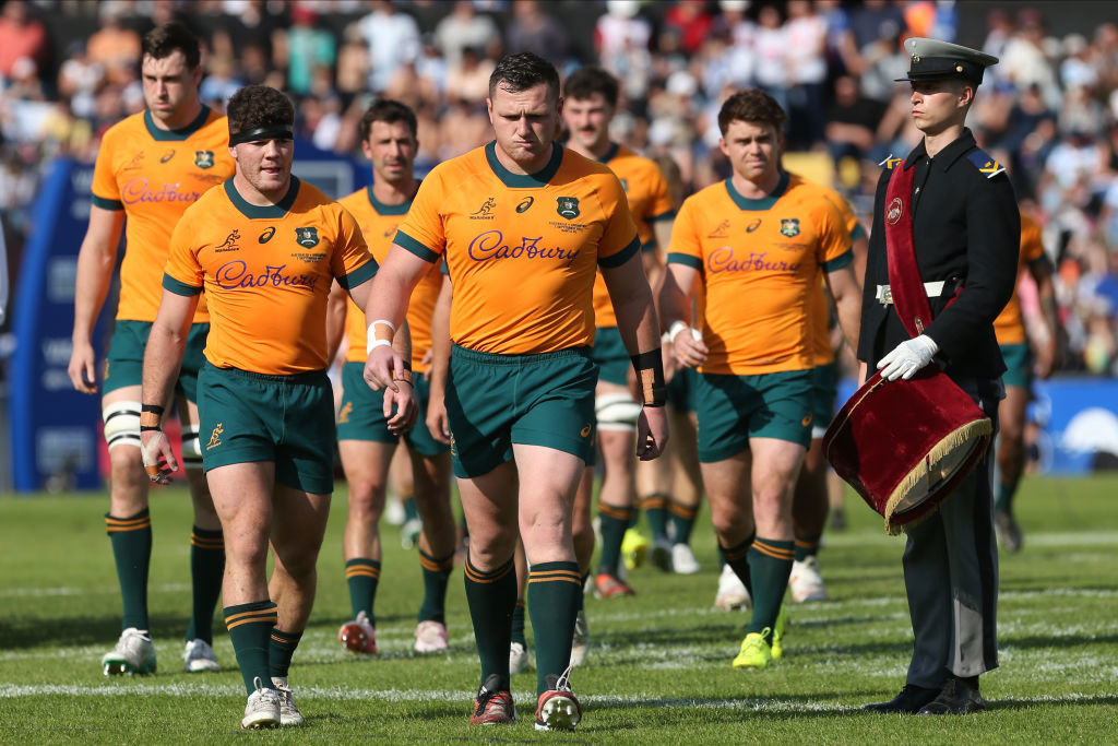 Players walk past an Argentine military band member before the match.