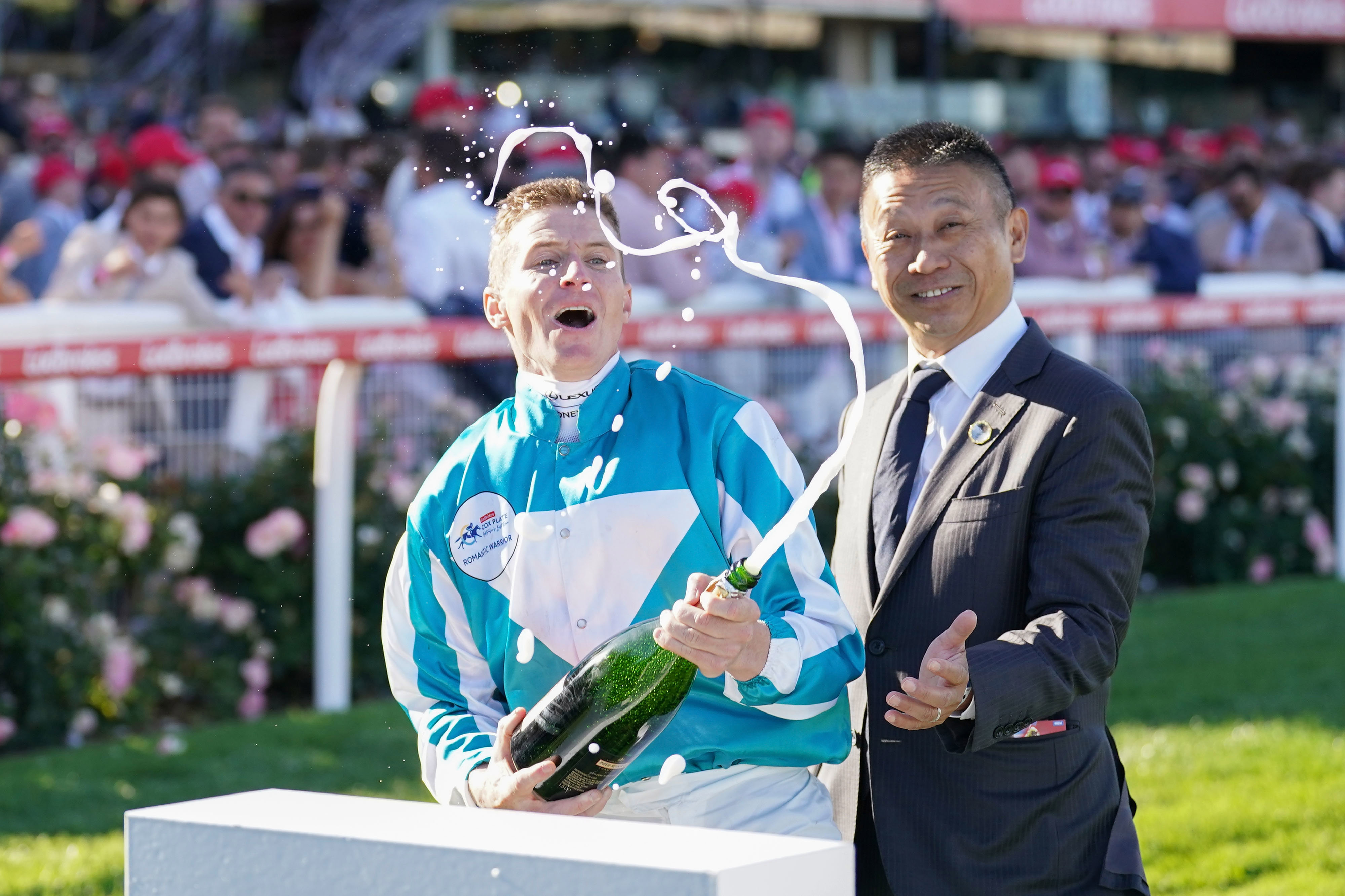 James McDonald sprays champagne watched by Danny Shum.