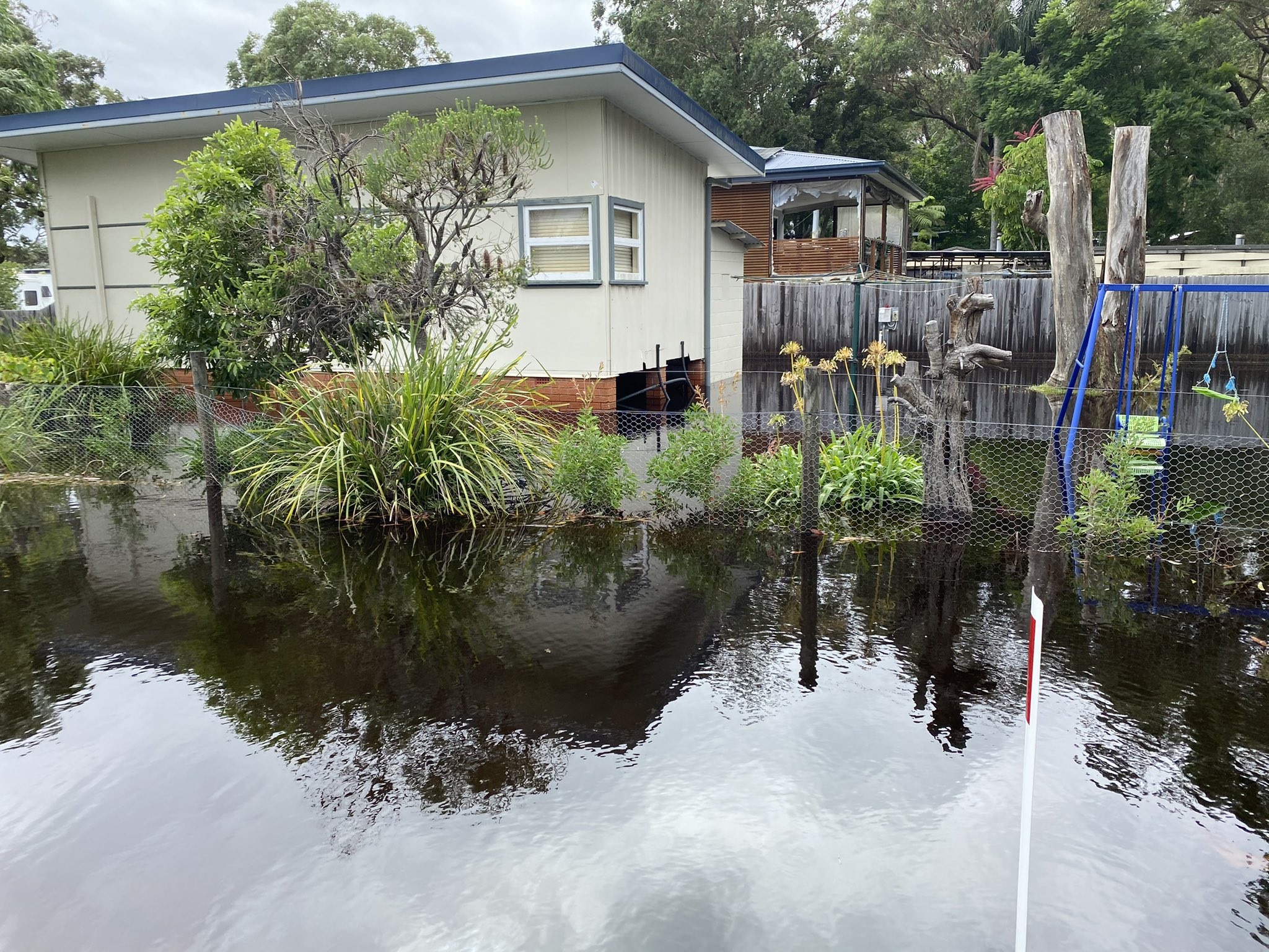 The front and backyards of a house in Lake Conjola on NSW's south coast are filled with floodwaters. 