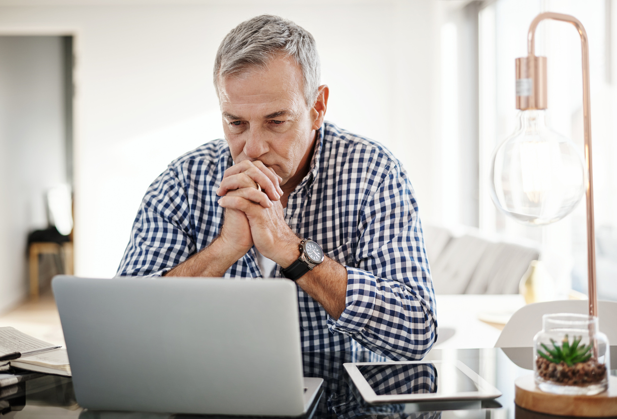 Shot of a mature man looking anxious while working on a laptop at home