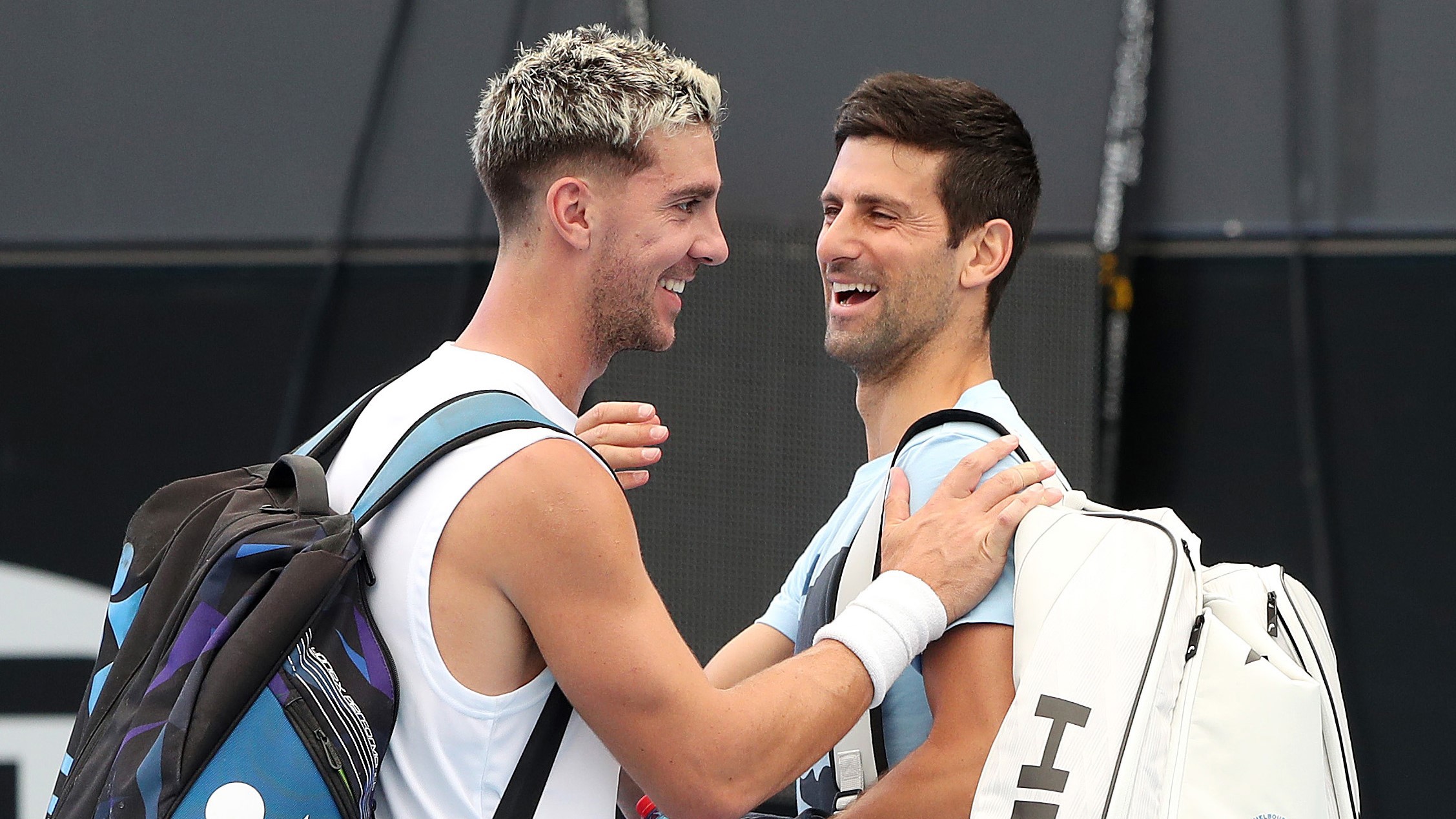 Thanasi Kokkinakis shakes hands with Novak Djokovic as they cross paths during a practice session ahead of the Adelaide International.