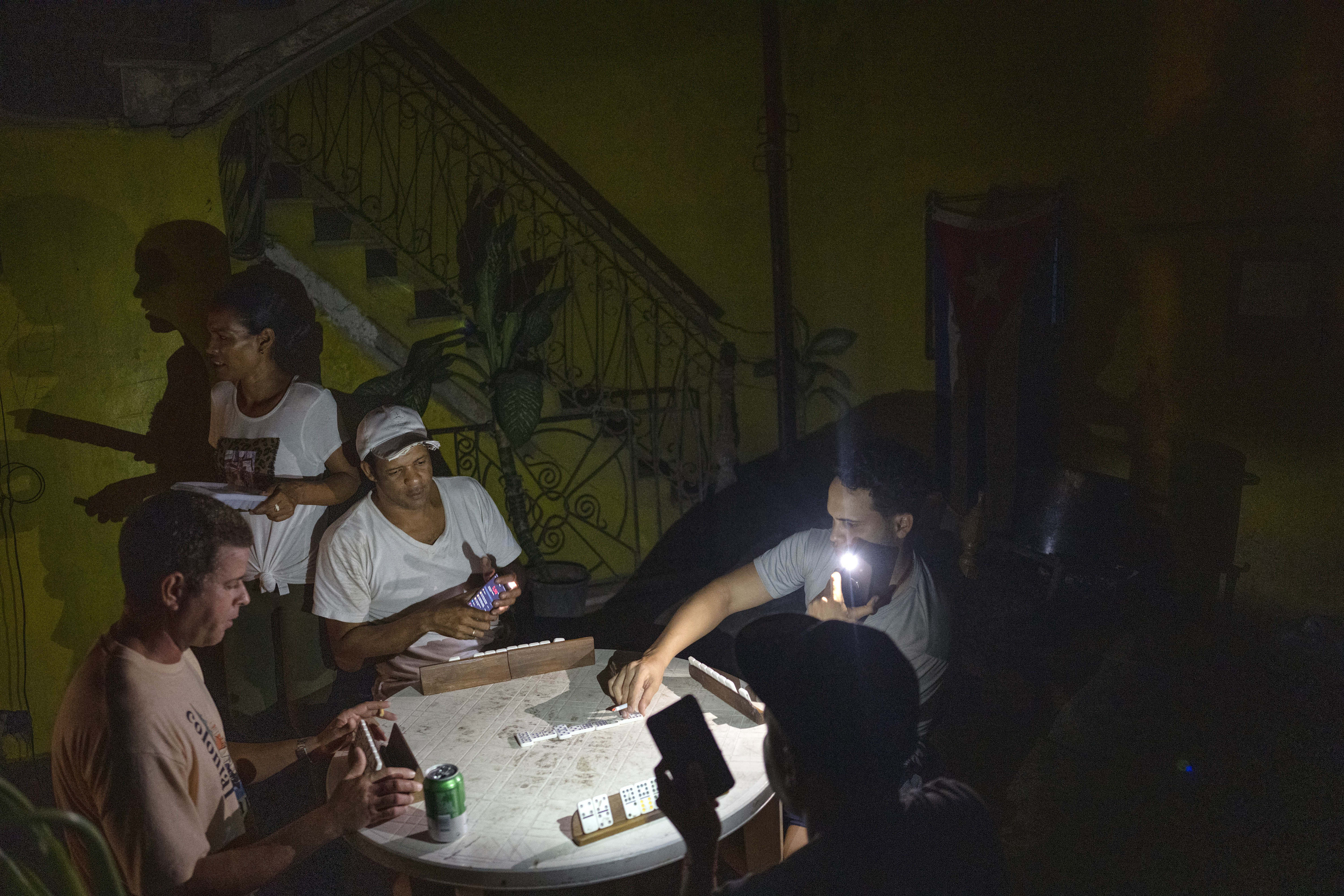 La gente juega al dominó con una linterna durante un apagón en La Habana, Cuba, el miércoles 28 de septiembre de 2022. 