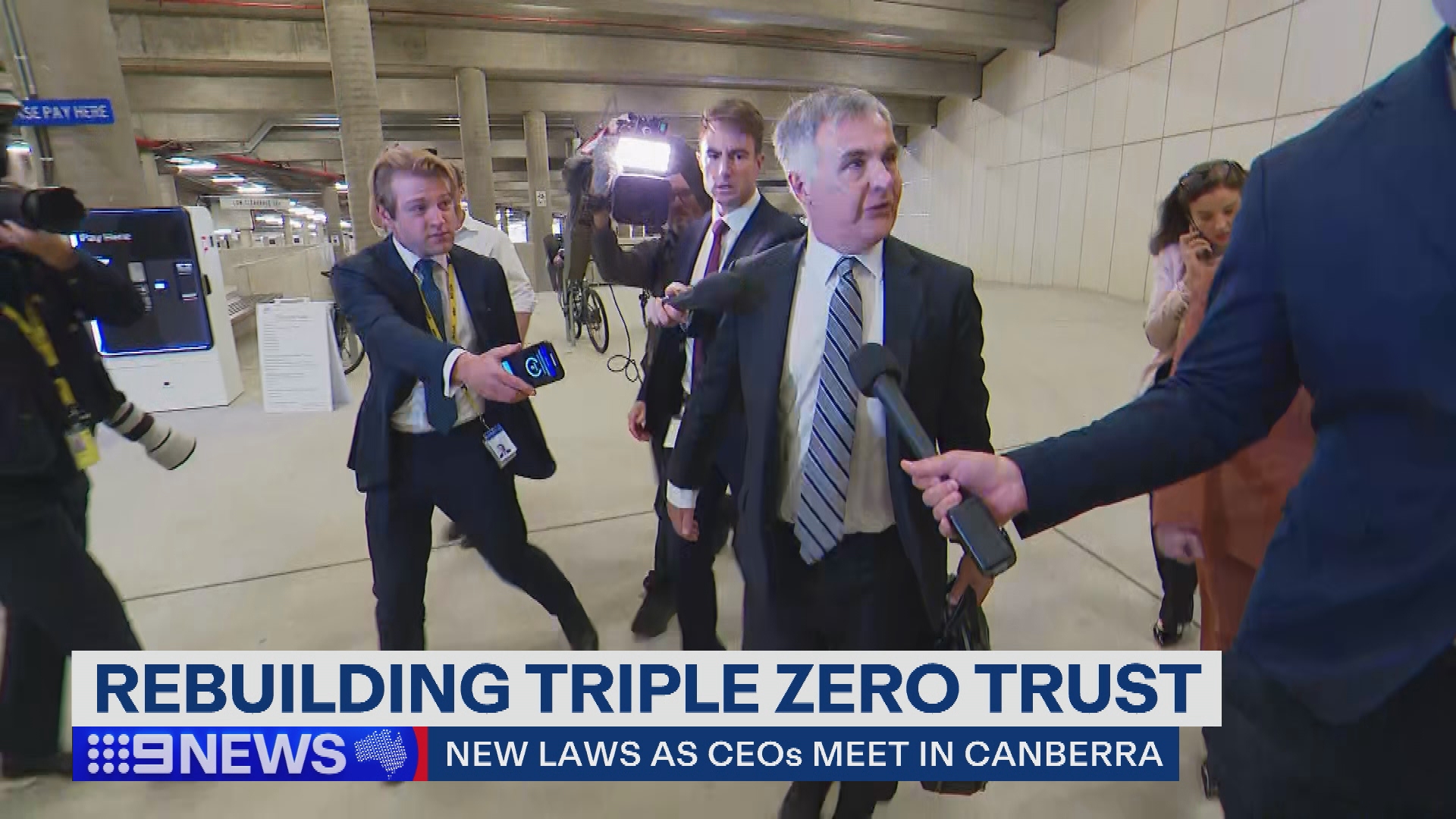 Optus CEO Stephen Rue, surrounded cameras and journalists ahead of his meeting with Anika Wells in Parliament House. 