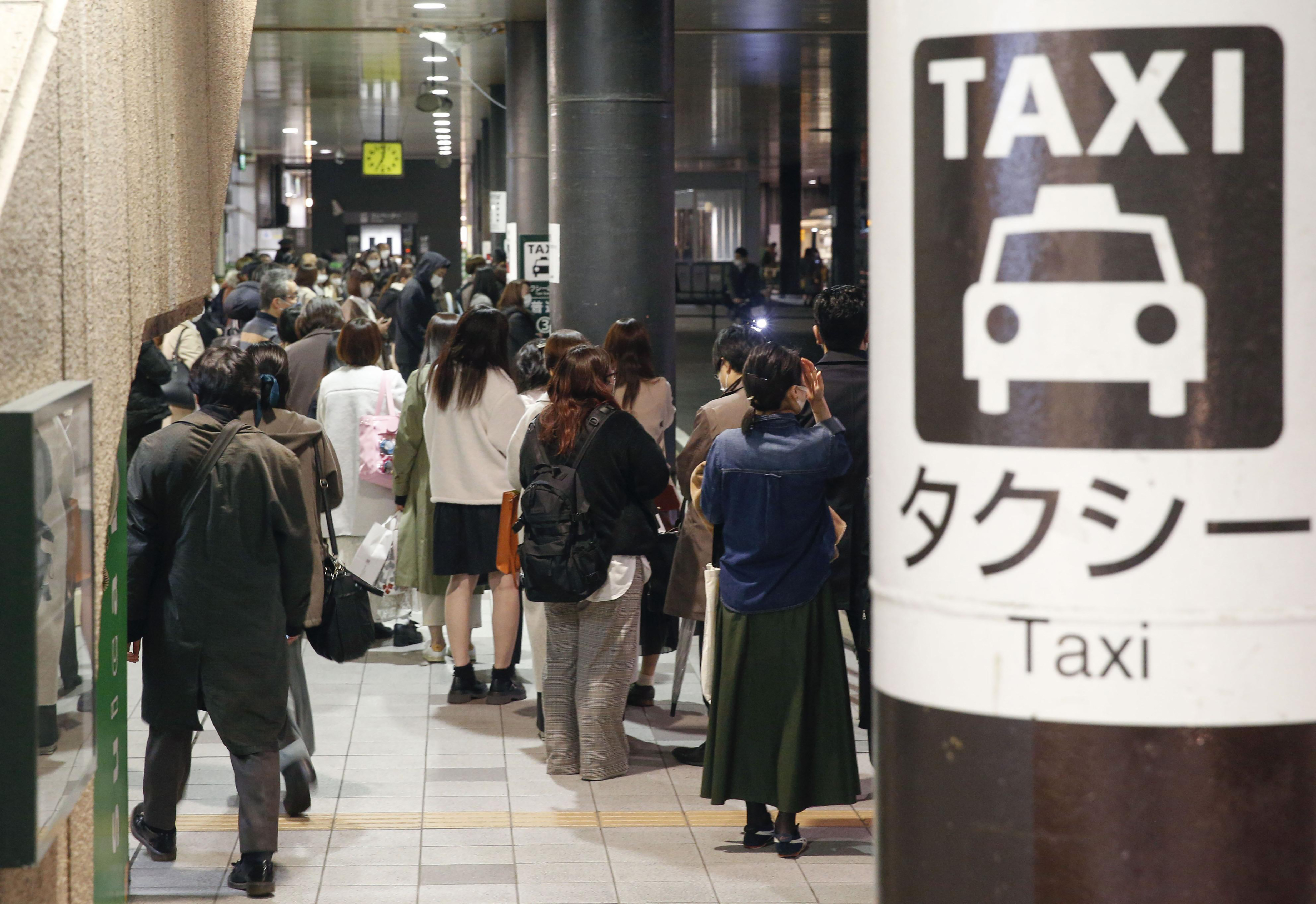 People queue up for taxi as train services are suspended following an earthquake in Sendai, Miyagi prefecture, Japan Saturday, March 20, 2021