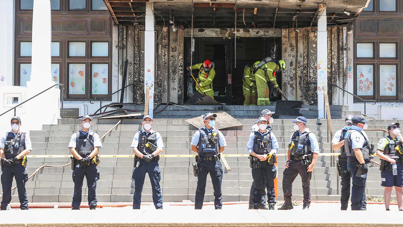 Firefighters responding at the fire-damaged front entrance of Old Parliament House following a protest.
