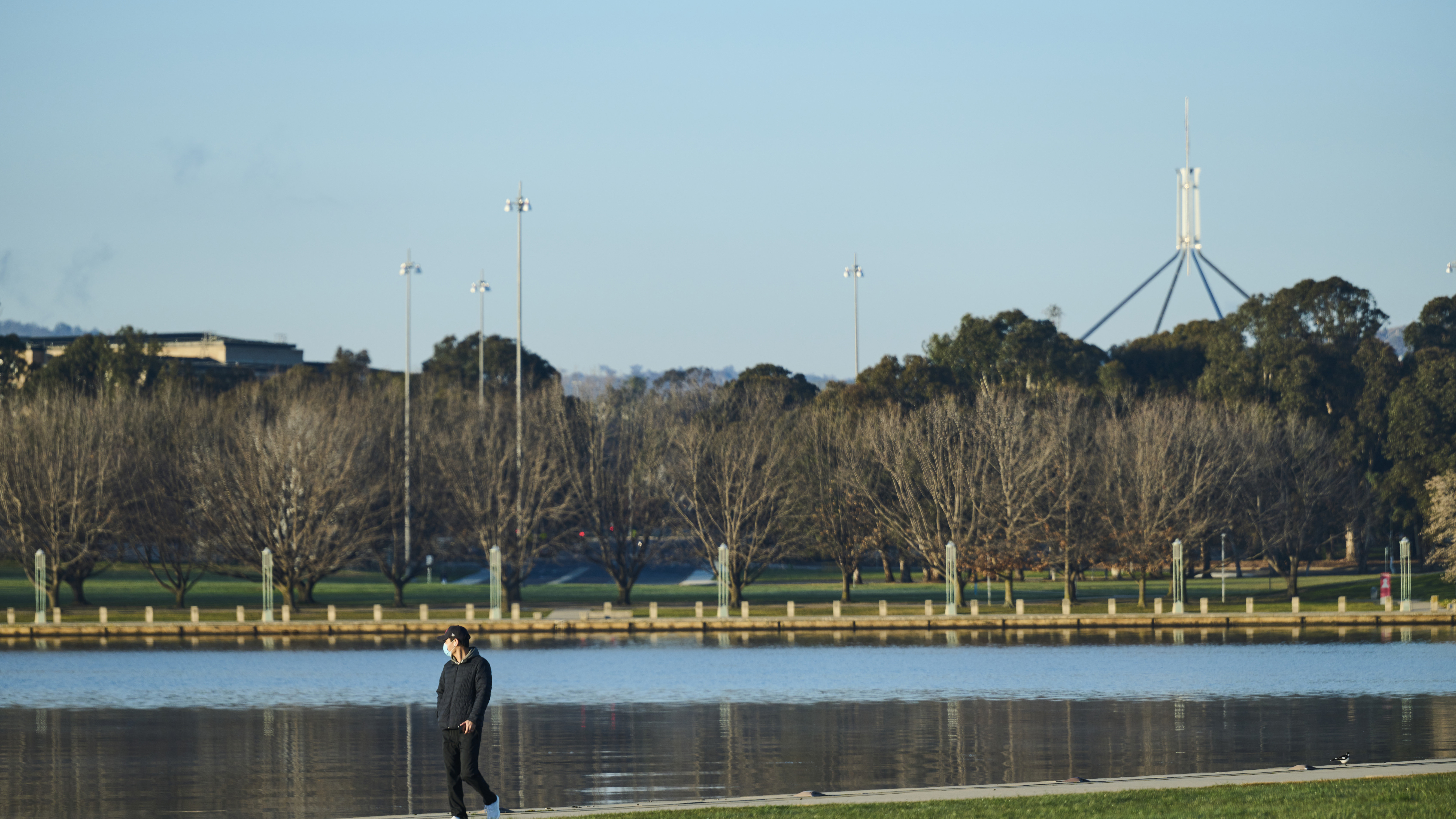 A walker wearing a mask beside Lake Burley Griffin in Canberra.
