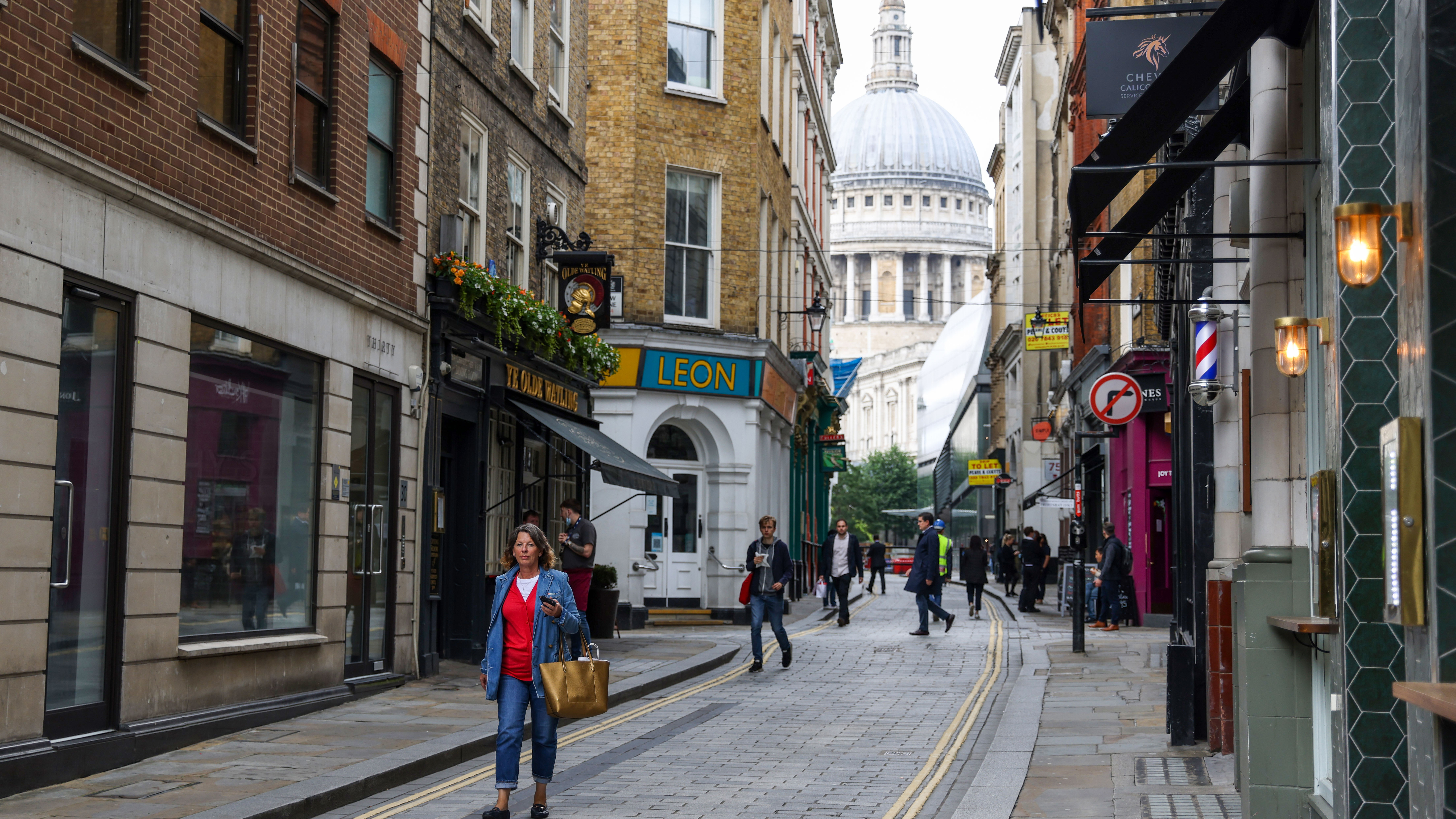 A pedestrian walks along Watling Street in view of St. Paul's Cathedral in London.