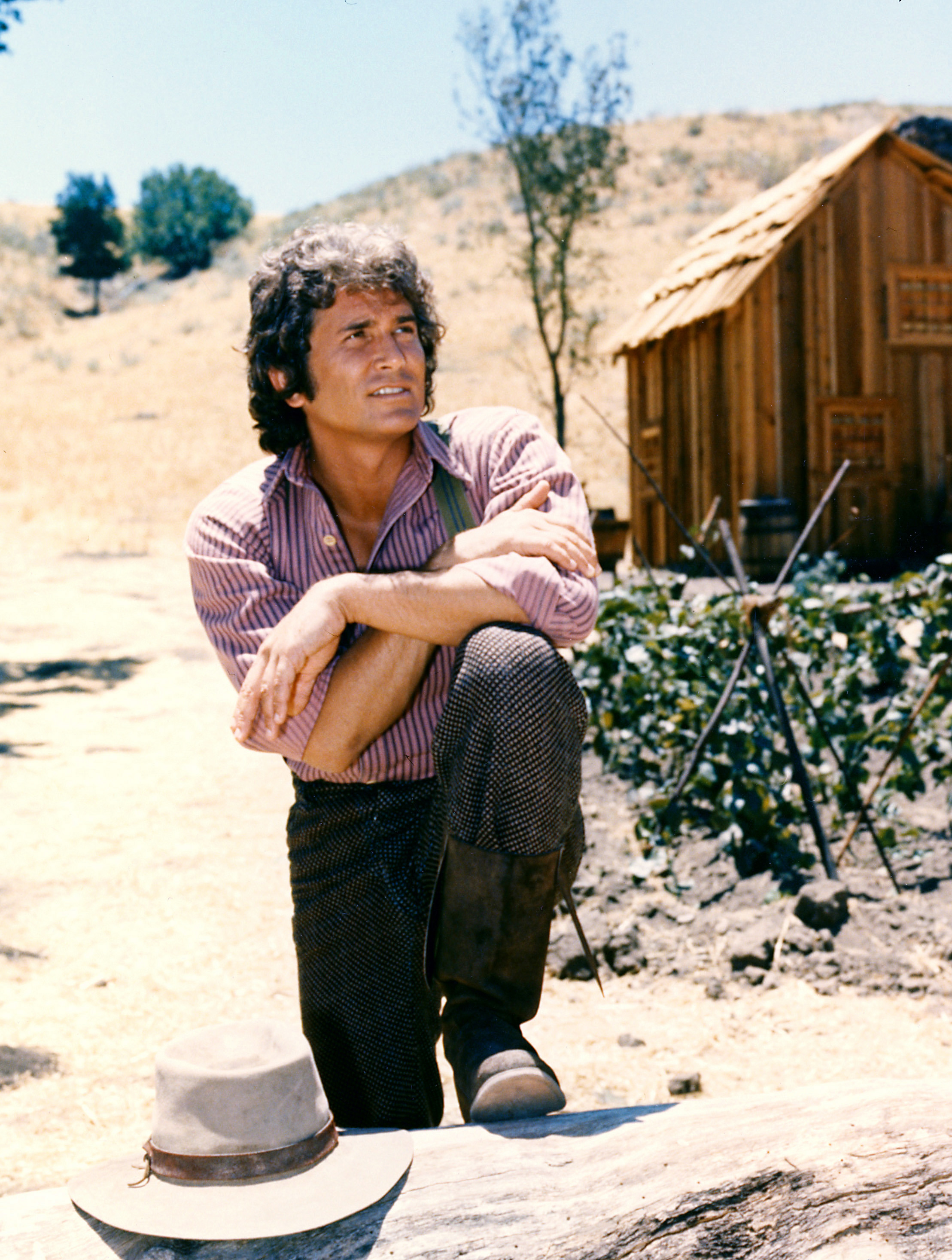 his knee with a log cabin the background in a portrait issued as publicity for the US television series, 'Little House on the Prairie', circa 1974. The drama, adapted from the novels by Laura Ingalls Wilder (1867-1957), starred Landon as 'Charles Ingalls'. (Photo by Silver Screen Collection/Getty Images)