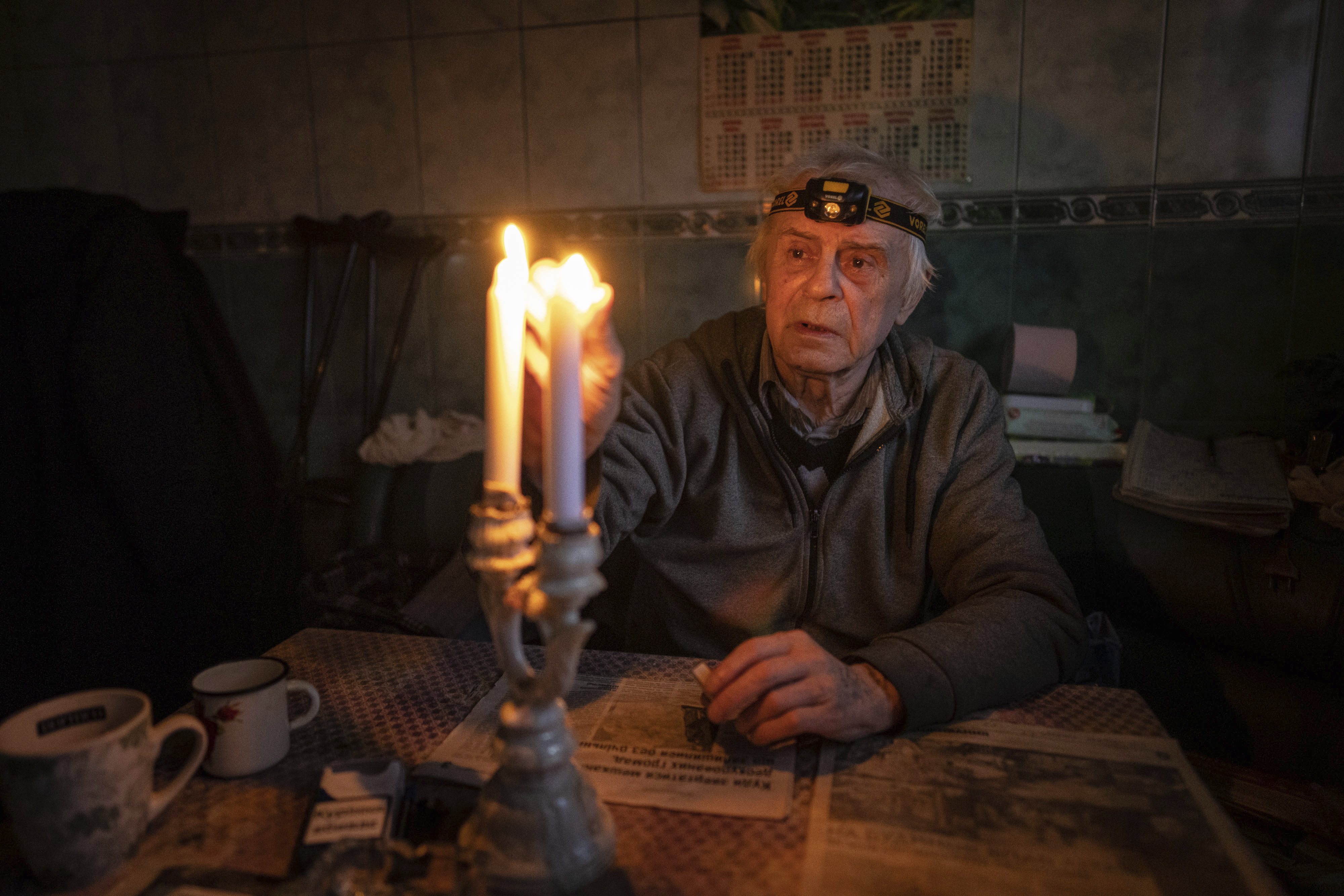 Volodymyr Dubrovsliy, a disabled pensioner, lights candles in his house after living without electricity for more than four months in Kupiansk, Kharkiv region, Ukraine, Wednesday, Dec. 28, 2022.