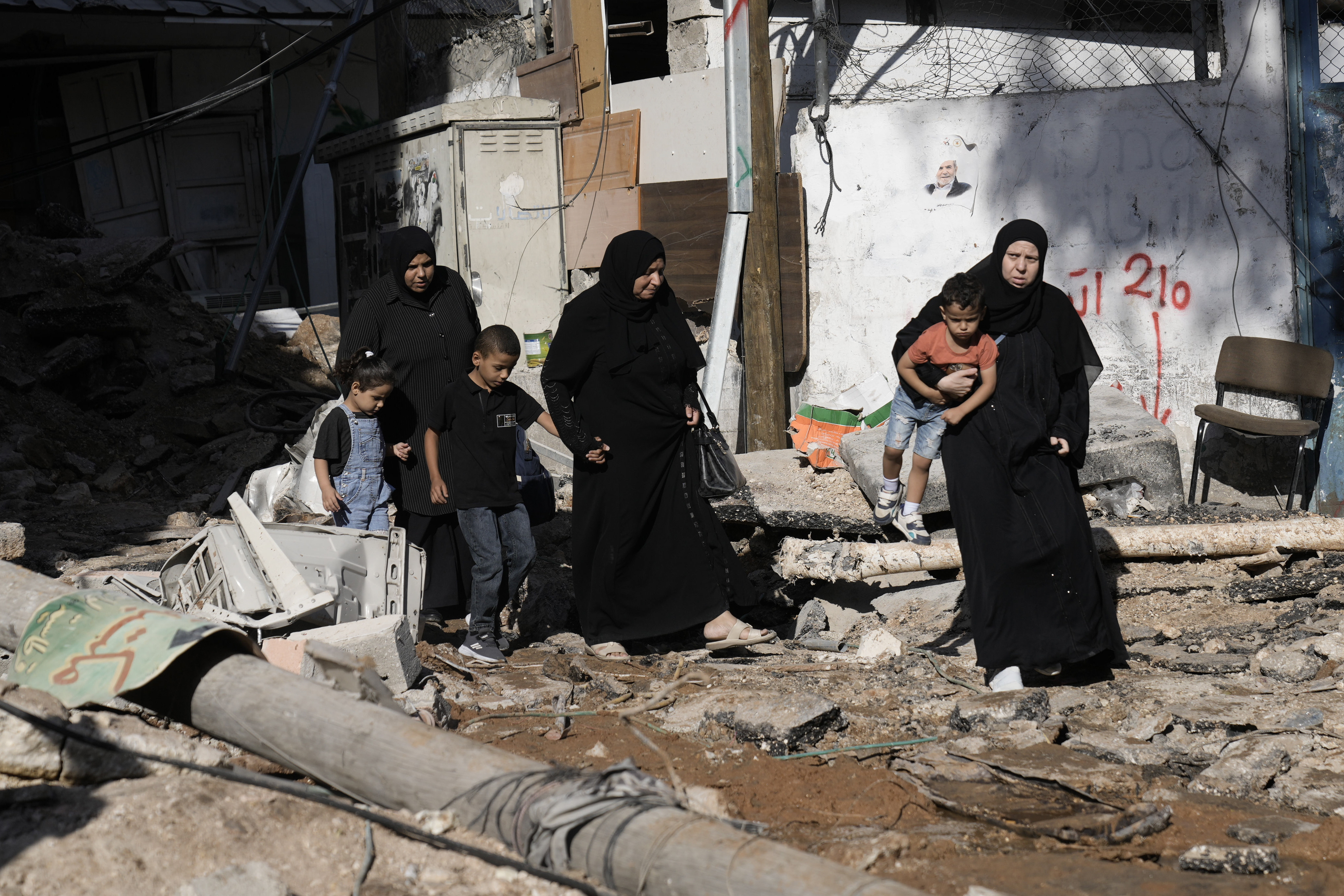 People look at destruction after an Israeli army raid on a Palestinian refugee camp, Nur Shams, in the West Bank, Friday, Oct. 20, 2023. 