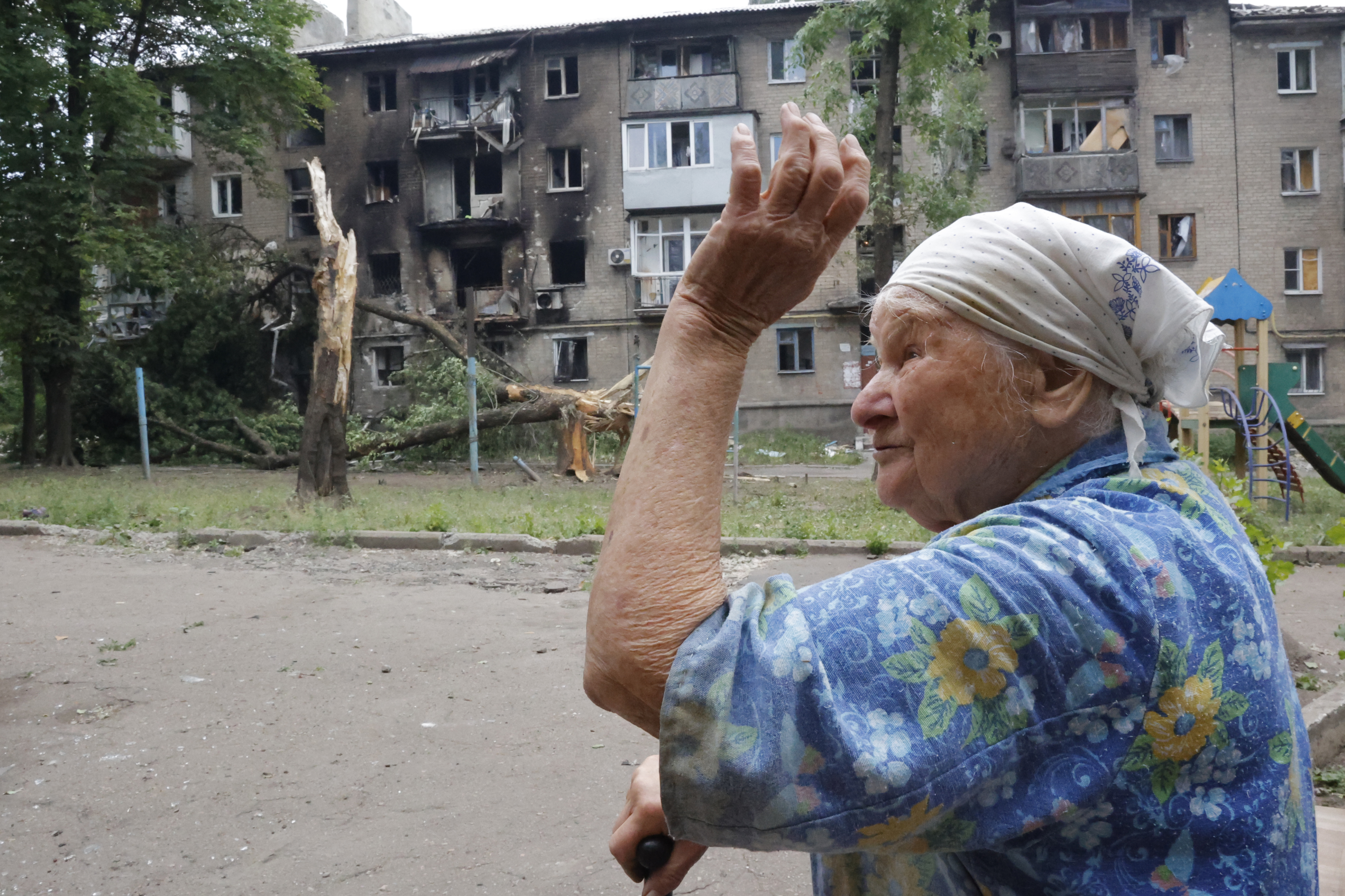 A woman gestures near an apartment building damaged during shelling in Donetsk, in territory under the government of the Donetsk People's Republic, eastern Ukraine, Wednesday, June 22, 2022.
