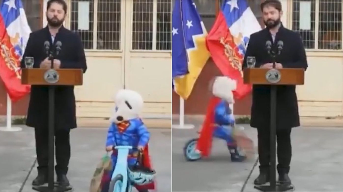 A child dressed as superman circling the Chilean president on a bike as he addresses the nation.