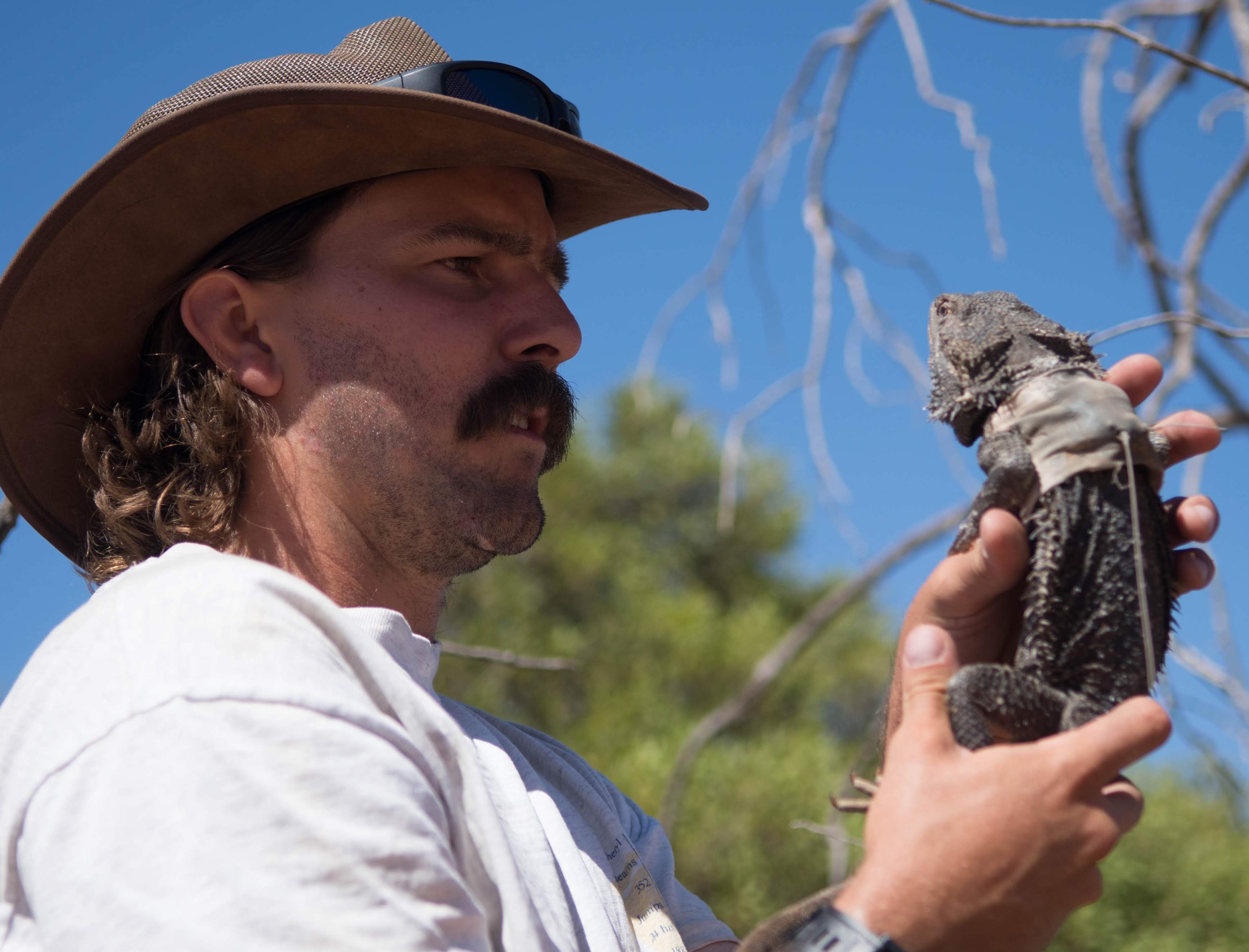 Dr Kristoffer Wild holding a bearded dragon in southwest Queensland.