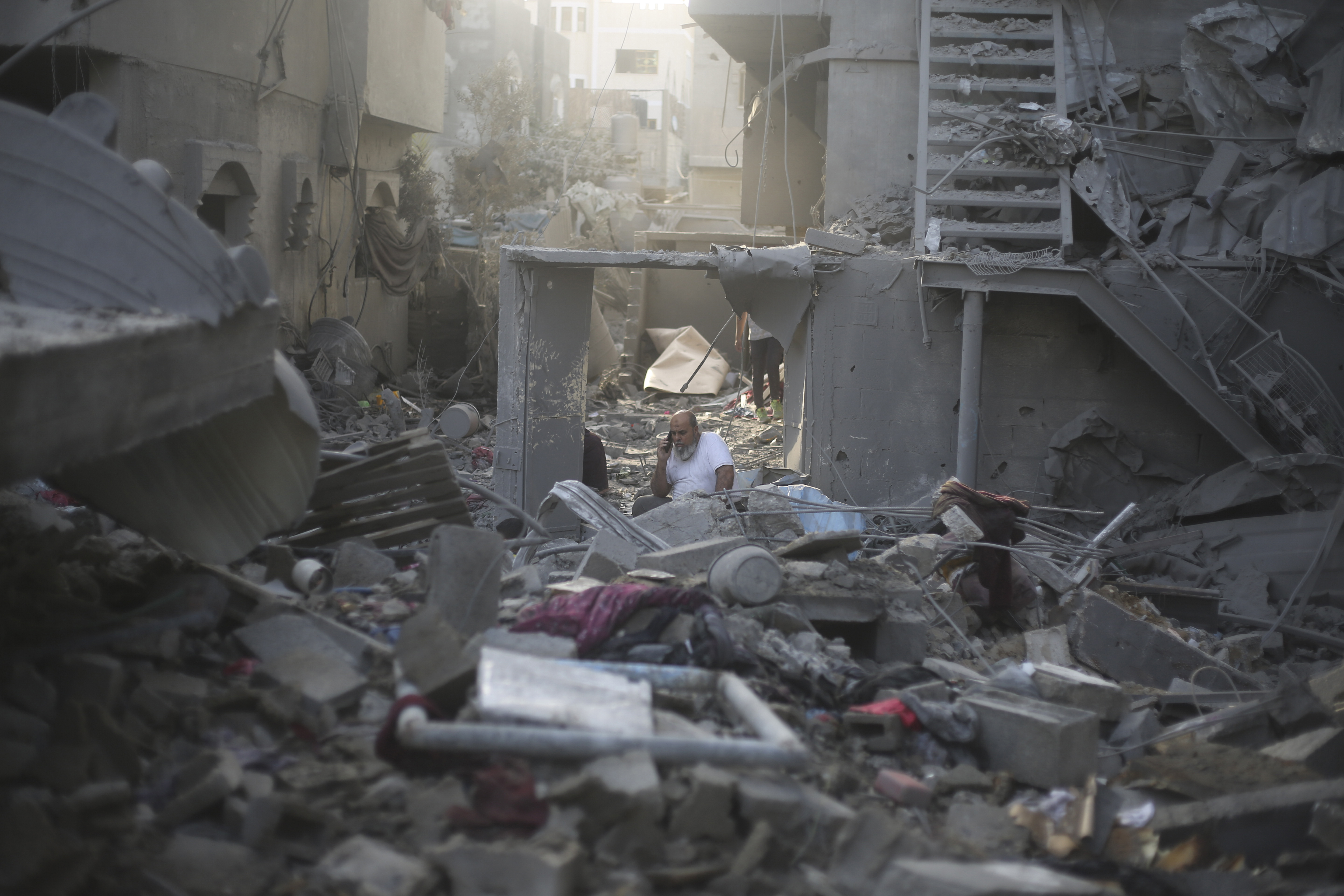 A Palestinian talks on the phone in the buildings destroyed in the Israeli bombardment
