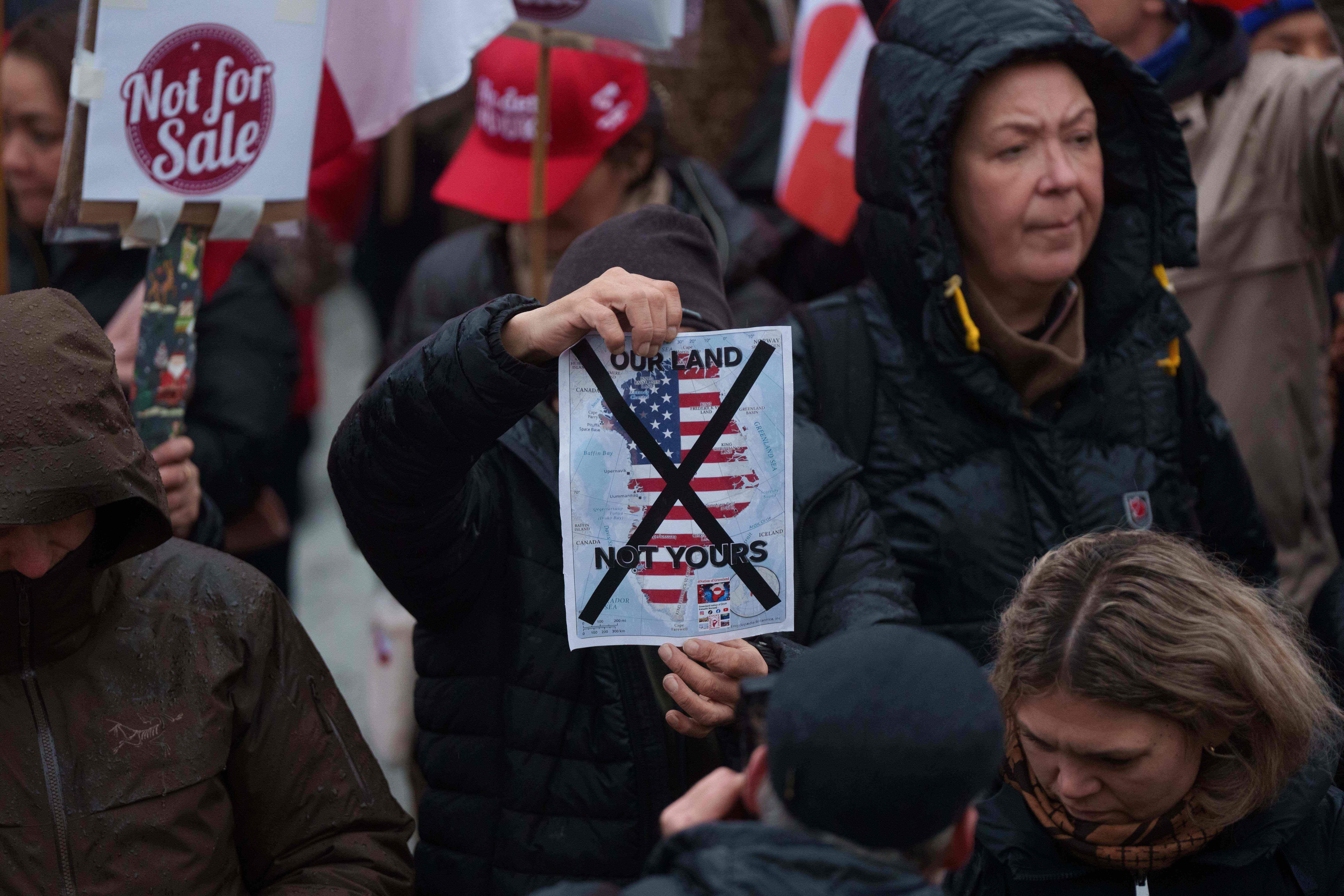 A man holds a map of Greenland covered in the American flag crossed out with an X during a protest against Trump's policy towards Greenland in front of the US consulate in Nuuk, Greenland, Saturday, Jan. 17, 2026.