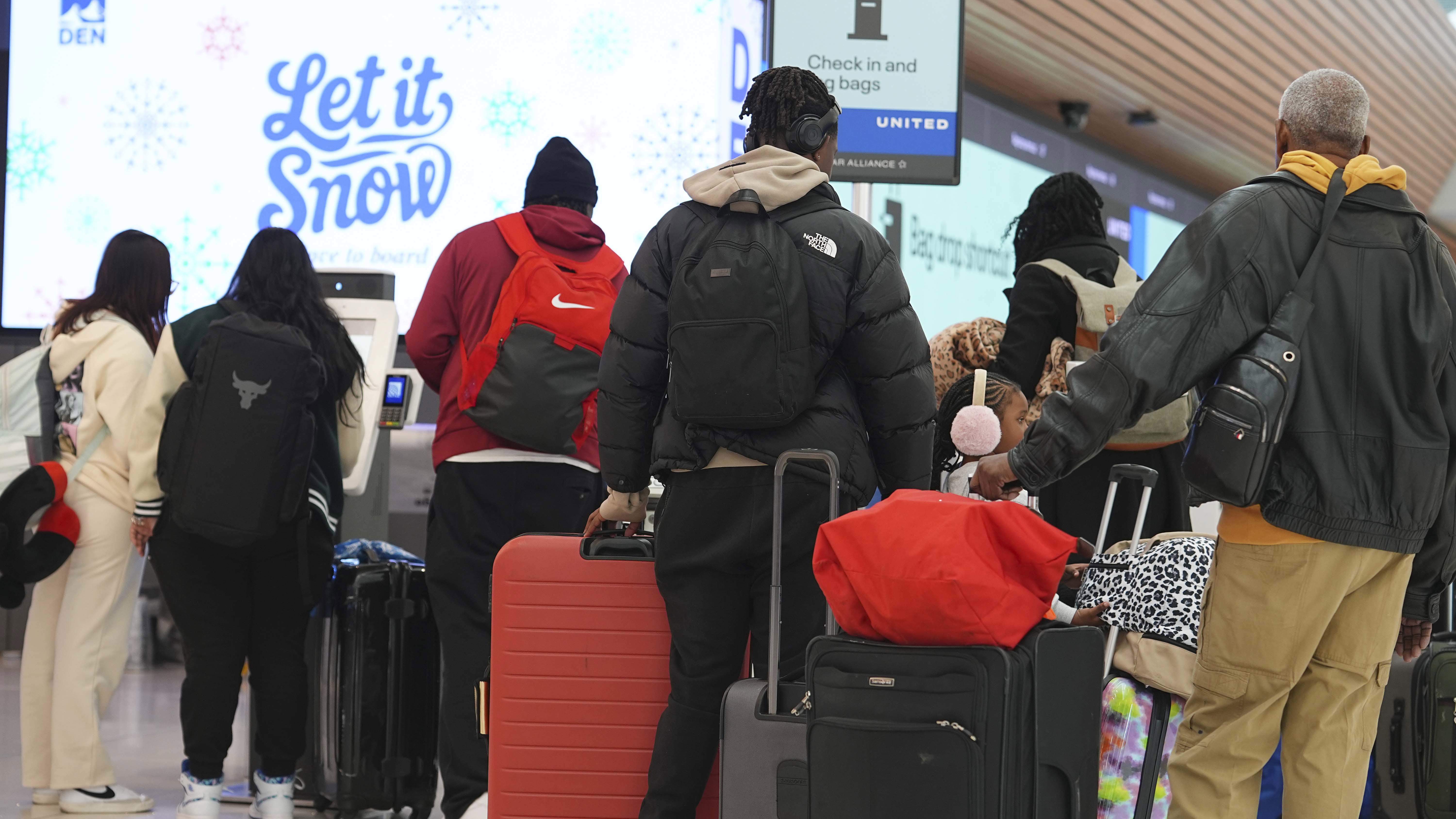 Travelers queue up at the United Airlines ticketing counter in Denver International Airport, Tuesday, Dec. 24, 2024, in Denver. (AP Photo/David Zalubowski)