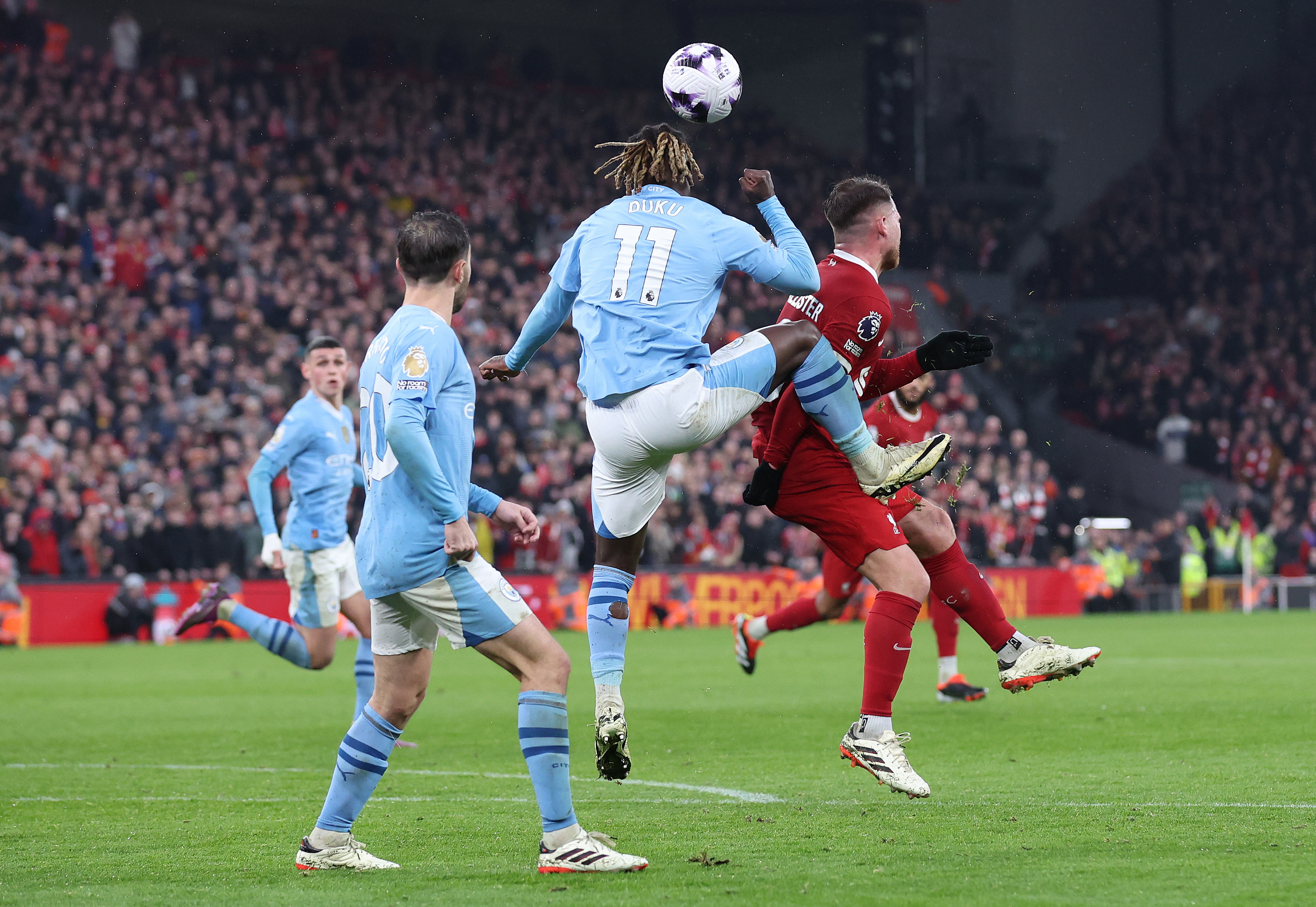 Jeremy Doku of Manchester City kicks Alexis Mac Allister of Liverpool during their Premier League match.