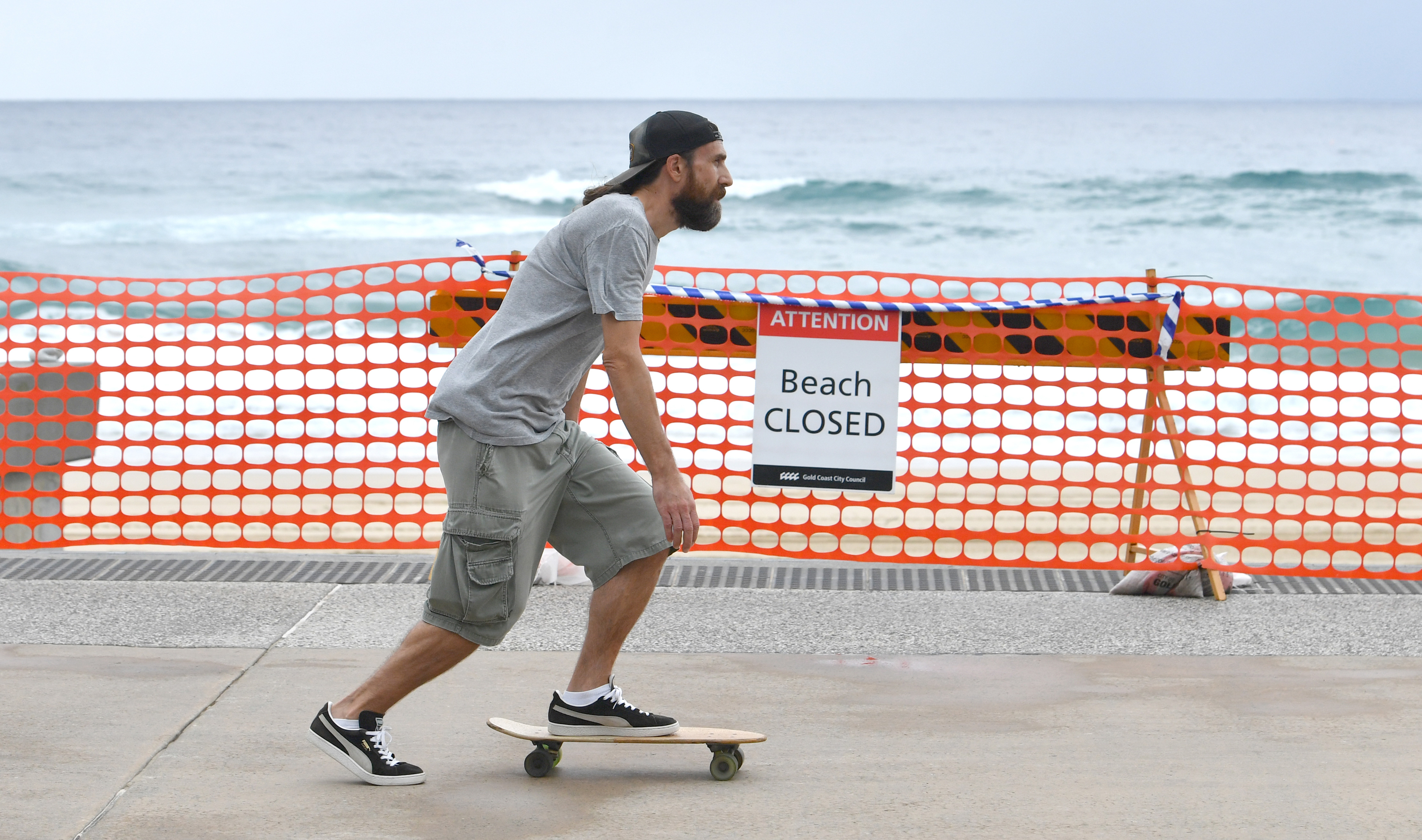 A man on a skateboard is seen going past the closed off Surfers Paradise beach on the Gold Coast, in April.