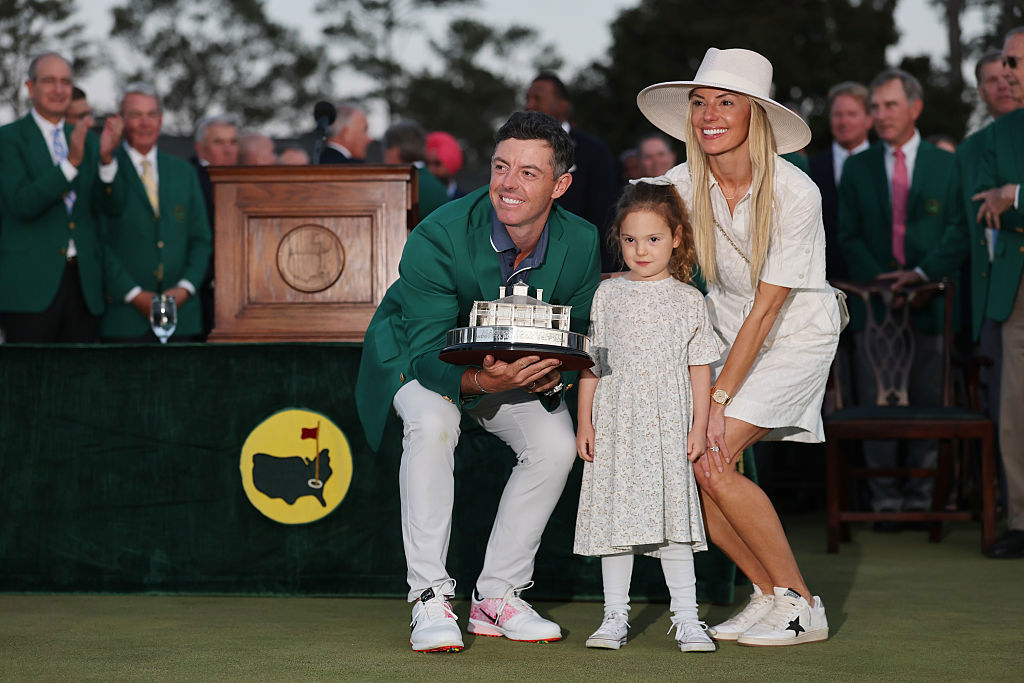 Rory McIlroy of Northern Ireland poses with daughter Poppy and wife Erica Stoll holding the Masters trophy during the Green Jacket Ceremony, 2025