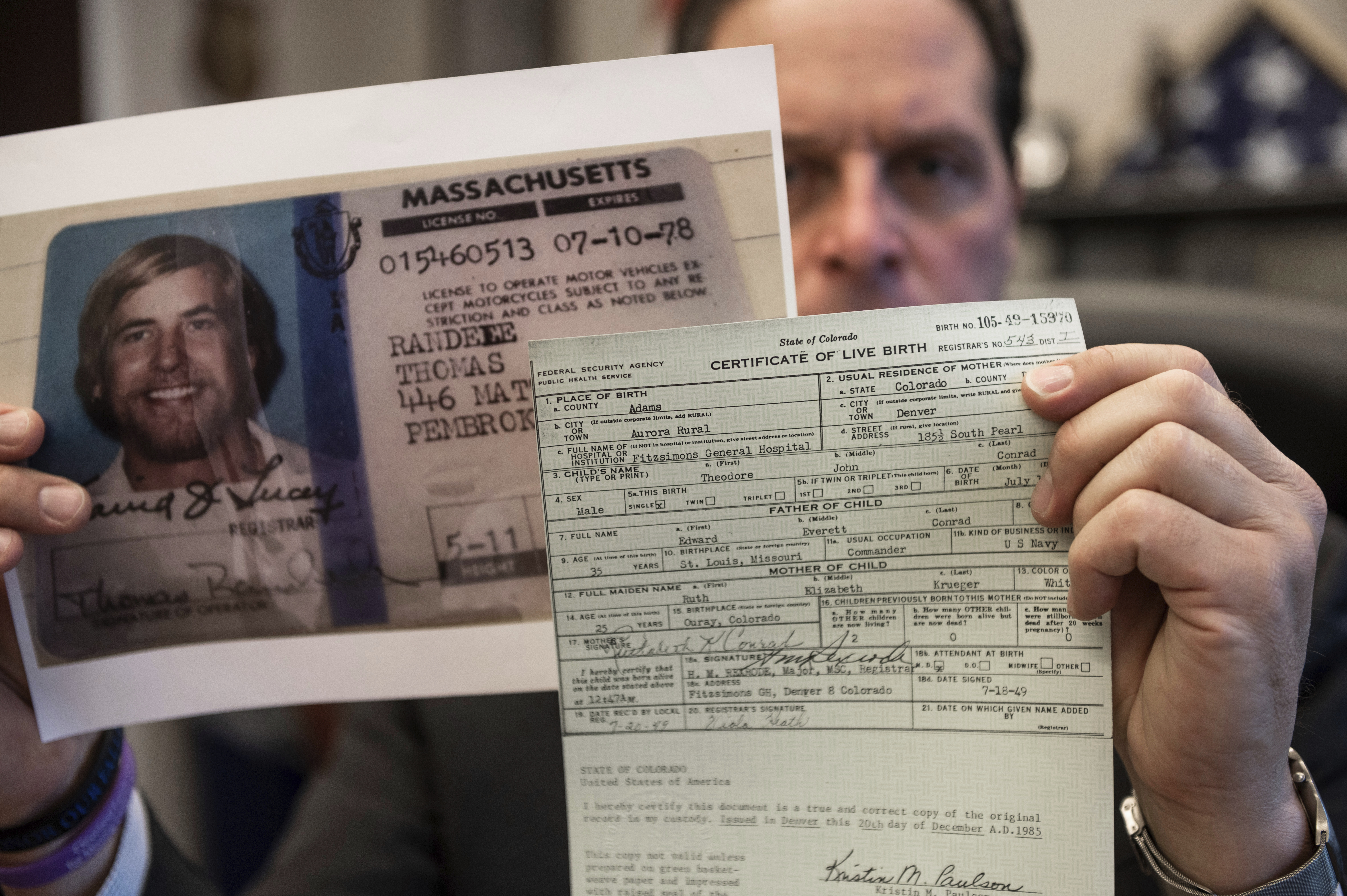 US Marshal Peter J. Elliott holds the birth certificate and a copy of the driver's license of Ted Conrad. 