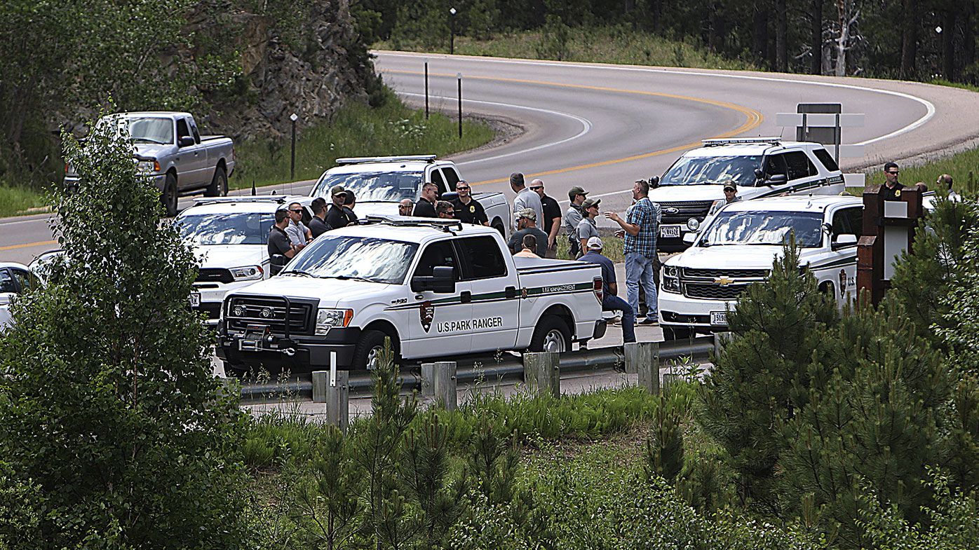 Law enforcement officers meet Thursday, July 2, 2020, at the site near Horse Thief Lake where traffic trying to enter the Mount Rushmore National Memorial, S.D., will be stopped and screened