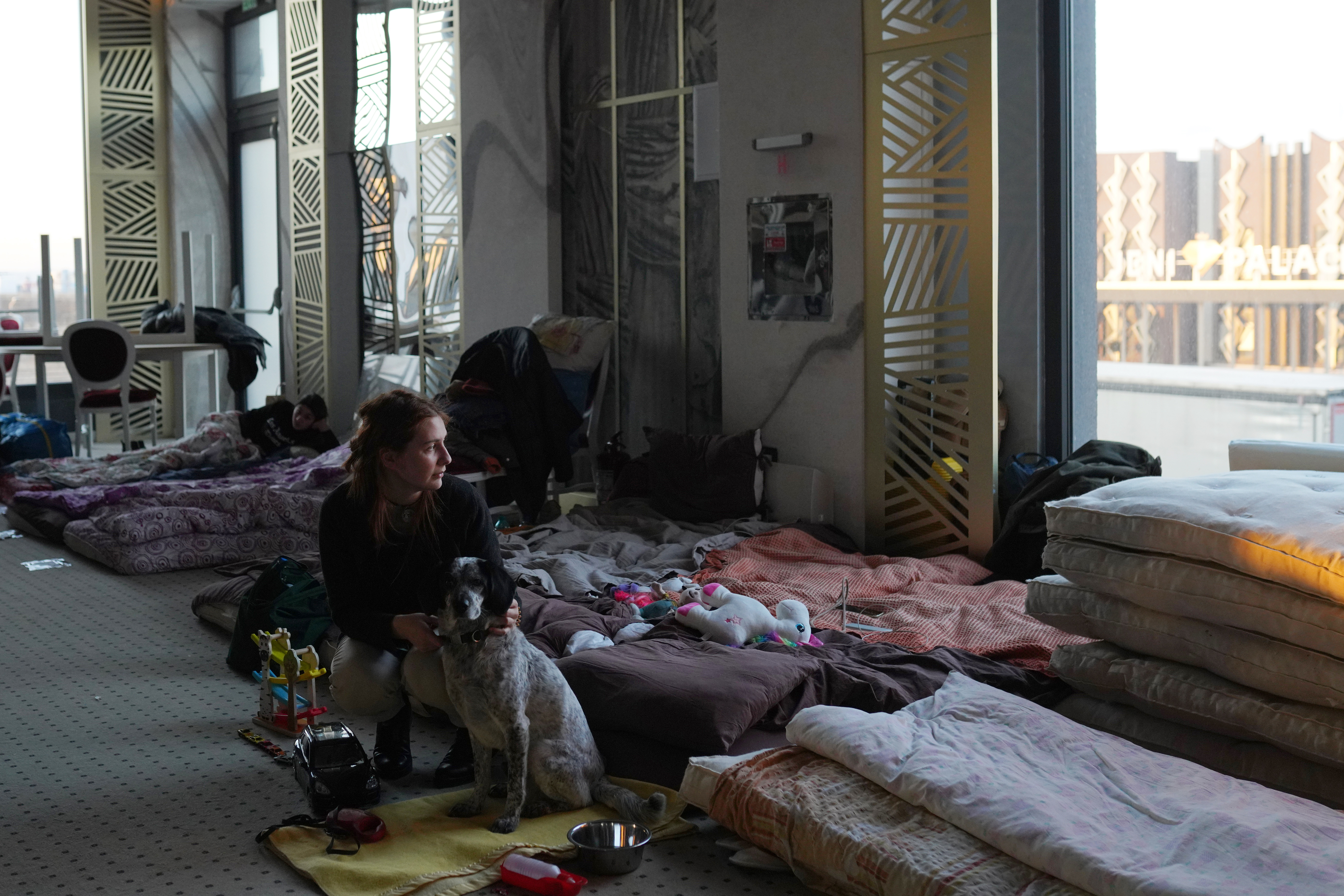 SUCEAVA, ROMANIA - [MARCH 18]: A young woman who fled the conflict in Ukraine holds her dog as she looks out the window in the ballroom in Mandachi Hotel and Spa, that was turned into a temporary shelter, on March 18, 2022 in Suceava, Romania. Ukrainian refugees continue to cross the border into Romania since Russia's invasion on February 24, some 500,000 Ukrainian citizens have entered Romania, with the majority reportedly making their way onto other countries in Western Europe.  (Photo by Andr