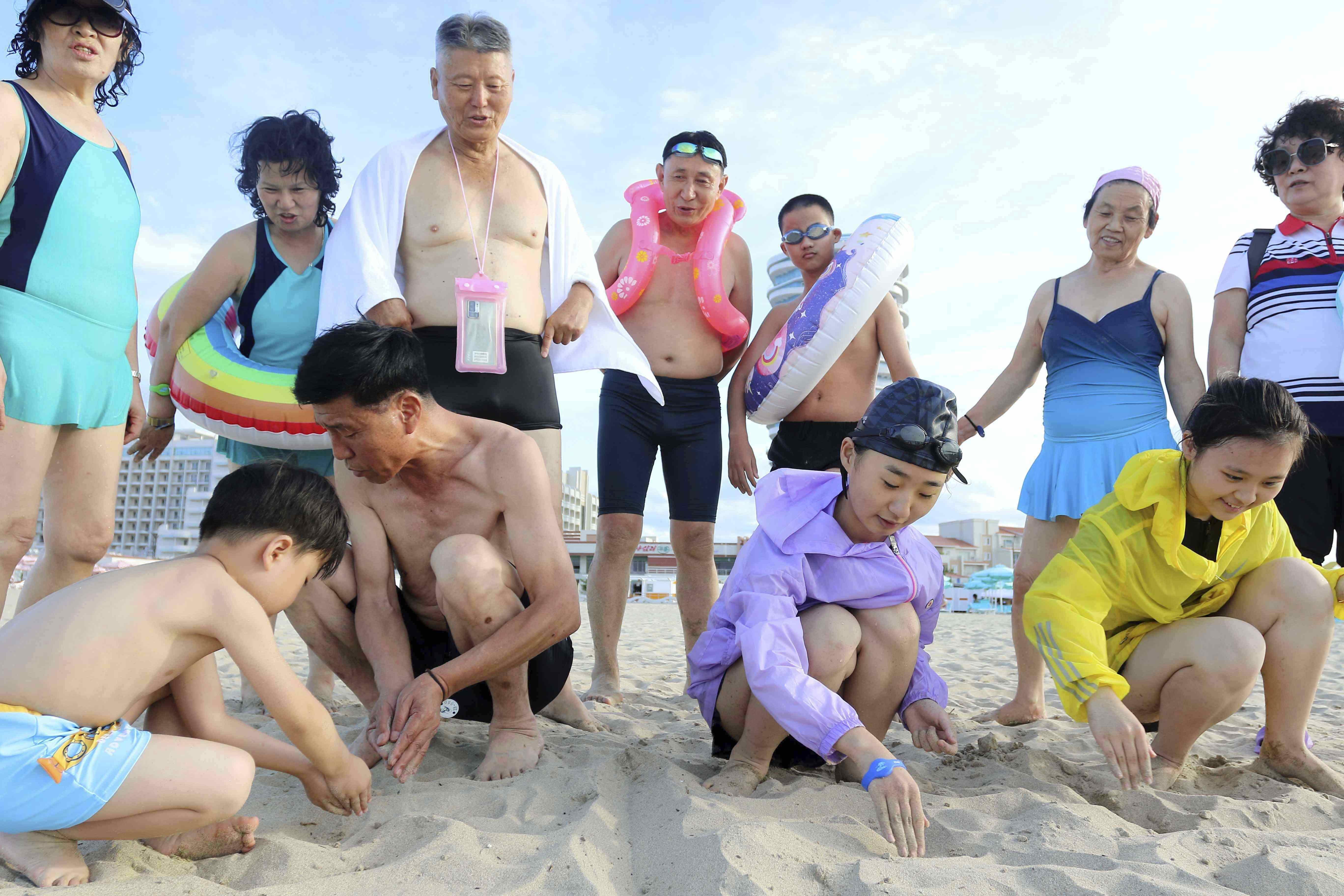 People look at children writing letters, &quot;our fatherland,&quot; on the beach at the Wonsan-Kalma resort in Wonsan, Kangwon Province, North Korea, Wednesday, July 2, 2025. (AP Photo/Jon Chol Jin)