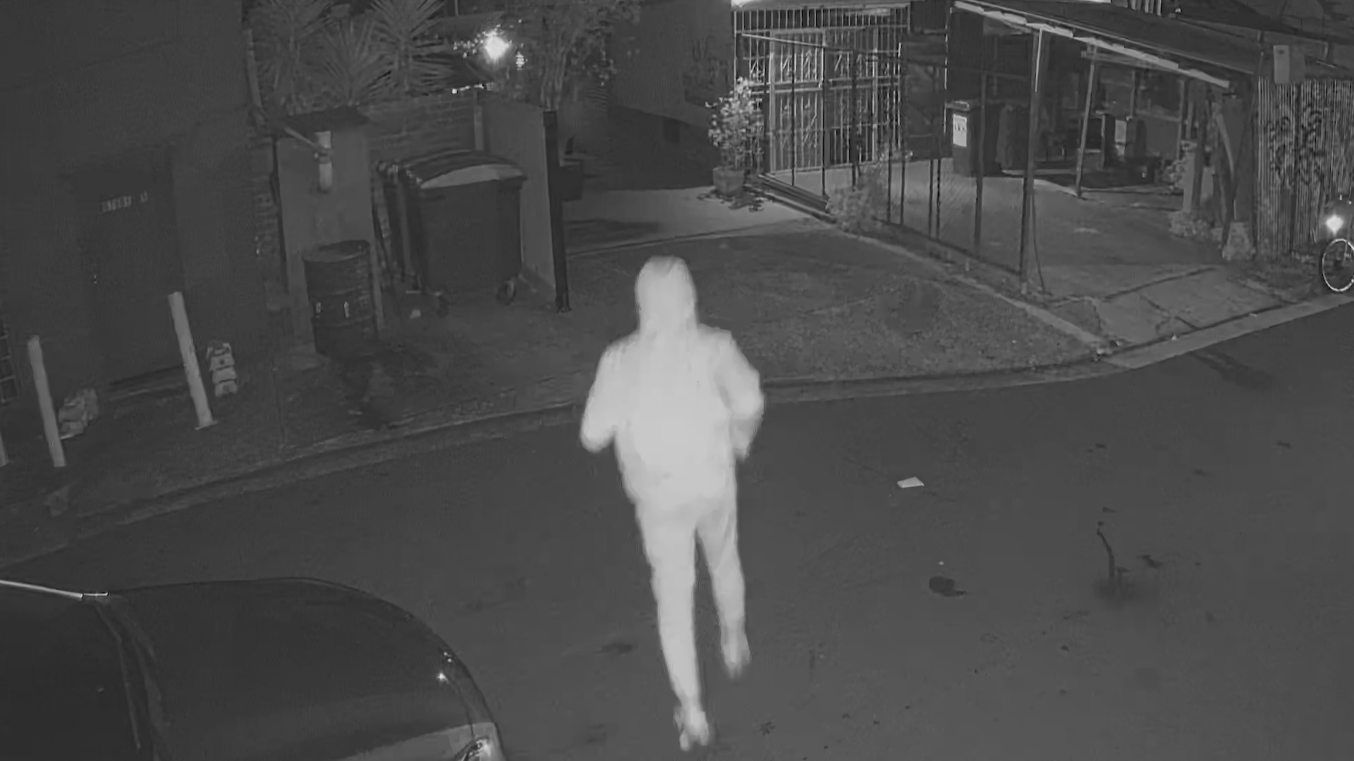 At the same location 24 hours earlier, a hooded figure is seen running in and out before the shop goes up in flames.