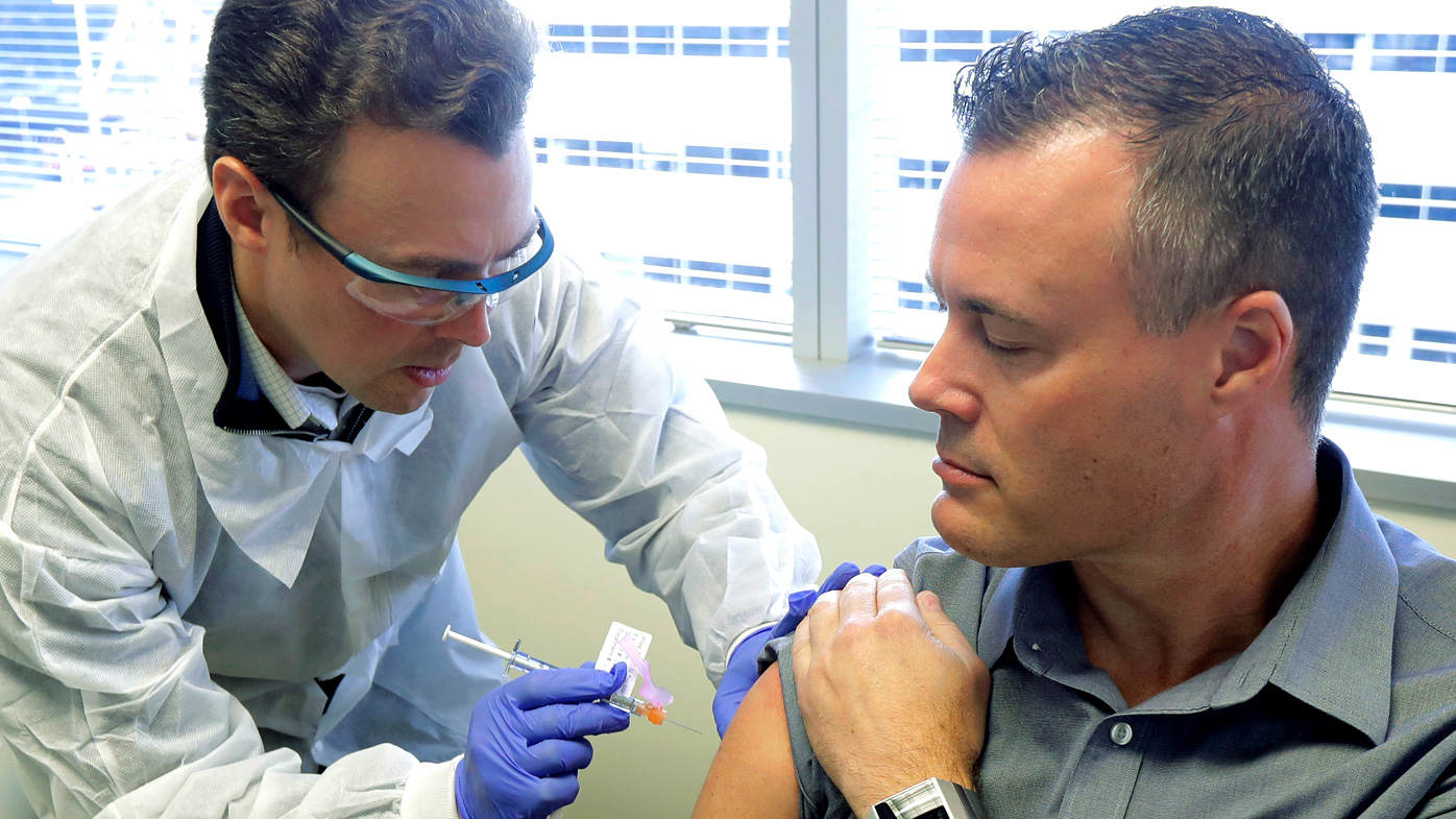 Pharmacist Michael Witte, left, gives Neal Browning a shot in the first-stage study of a potential coronavirus vaccine