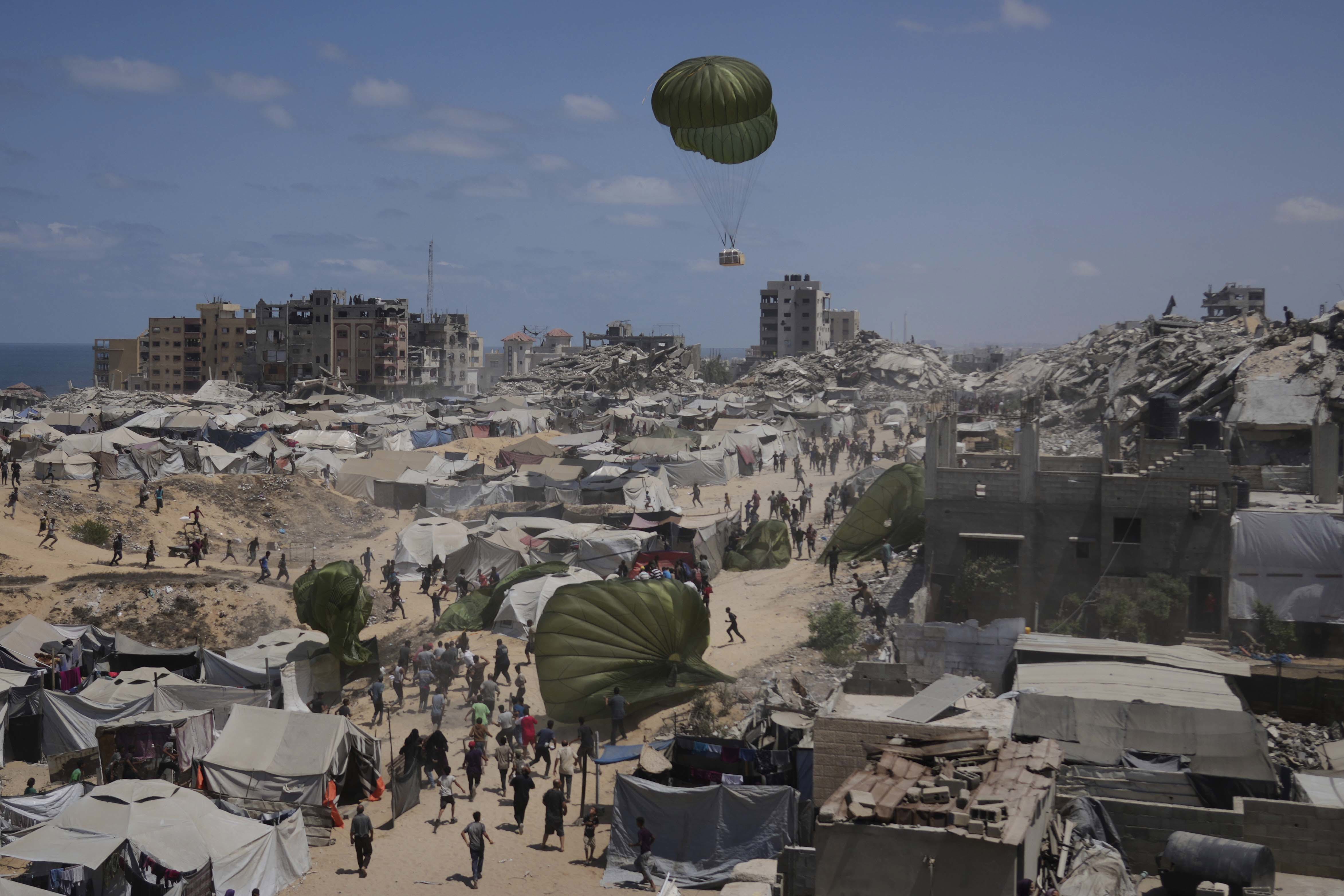 Palestinians rush to collect humanitarian aid airdropped by parachutes into Gaza City, northern Gaza Strip, Aug. 7, 2025. (AP Photo/Jehad Alshrafi)