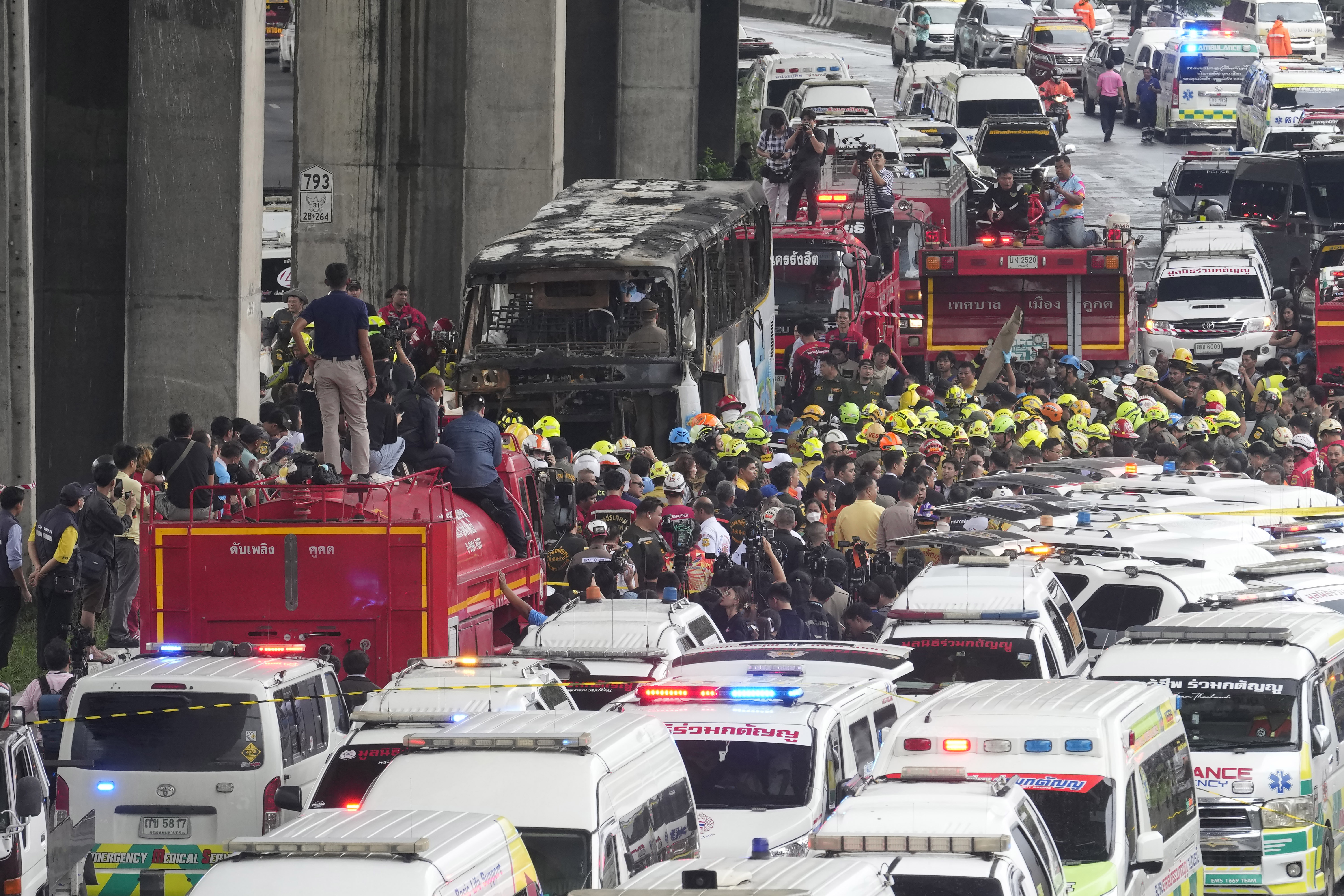 Rescuers gather at the site of a bus that caught fire, carrying young students with their teachers, in suburban Bangkok.