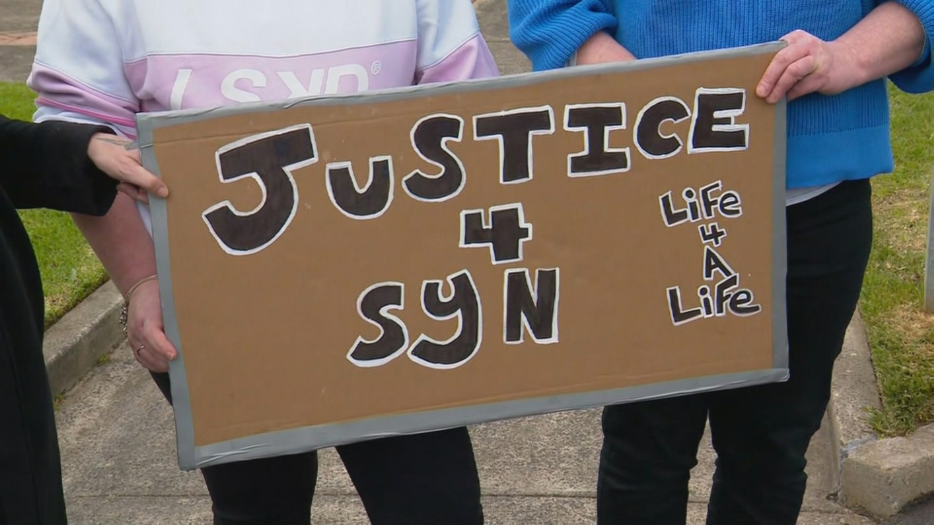 A cardboard sign reading "Justice 4 Syn".