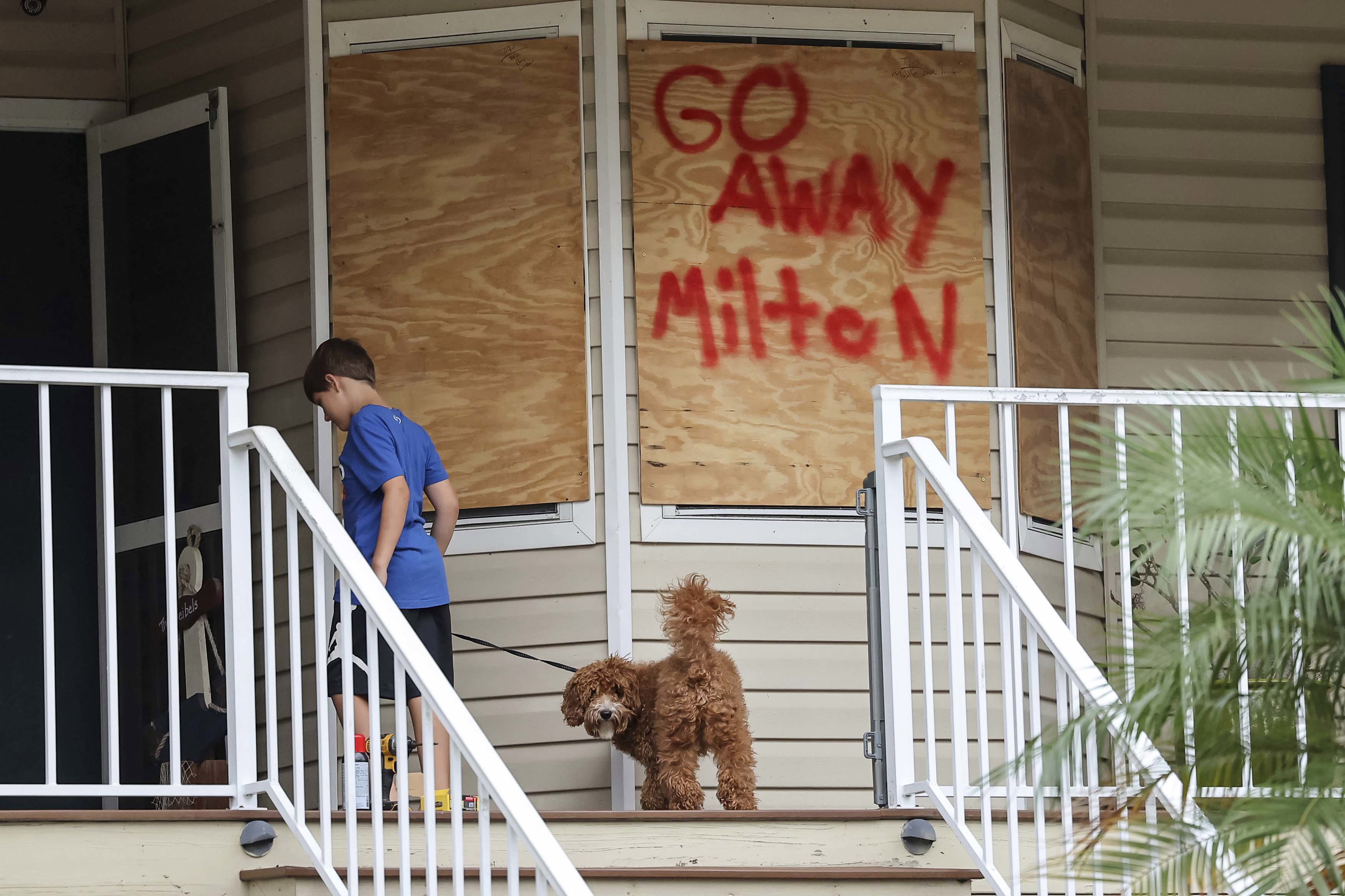 Noah Weibel y su perro Cookie suben las escaleras de su casa mientras su familia se prepara para el huracán Milton el lunes 7 de octubre de 2024 en Port Richey, Florida.