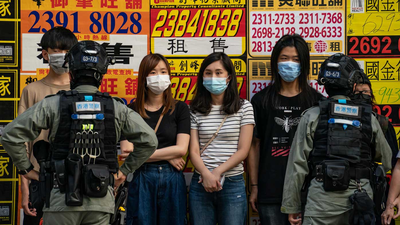 Riot police stop and search people during a protest against the national security law.