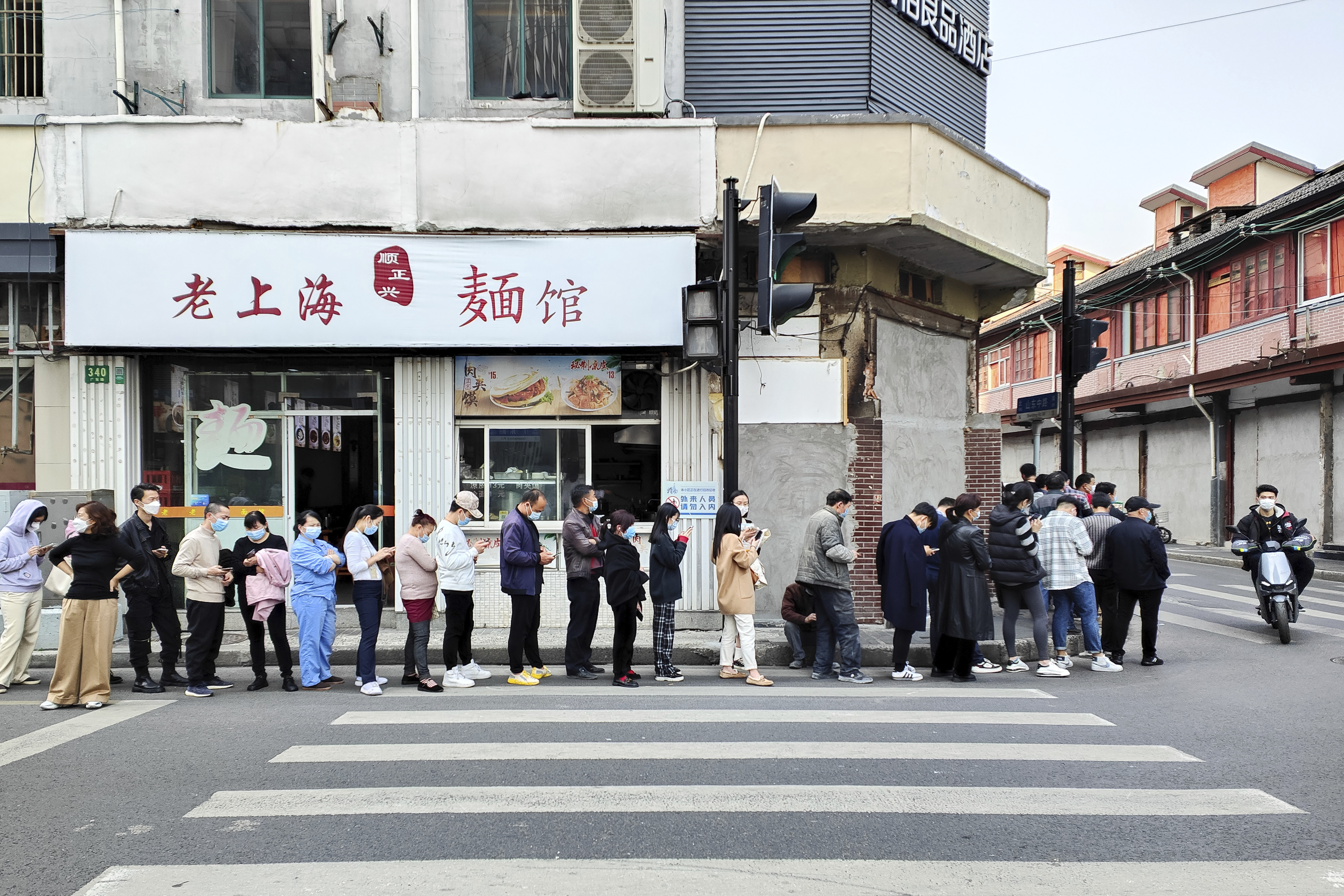 Residents line up near a noodle shop along a street for the COVID-19 test at a hospital in Shanghai. 