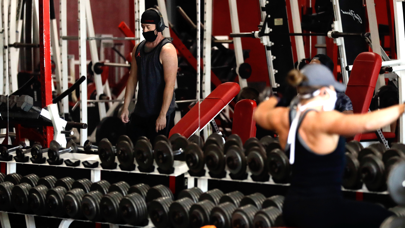 People work out at a gym wearing protective face masks and adopting social distancing measures.