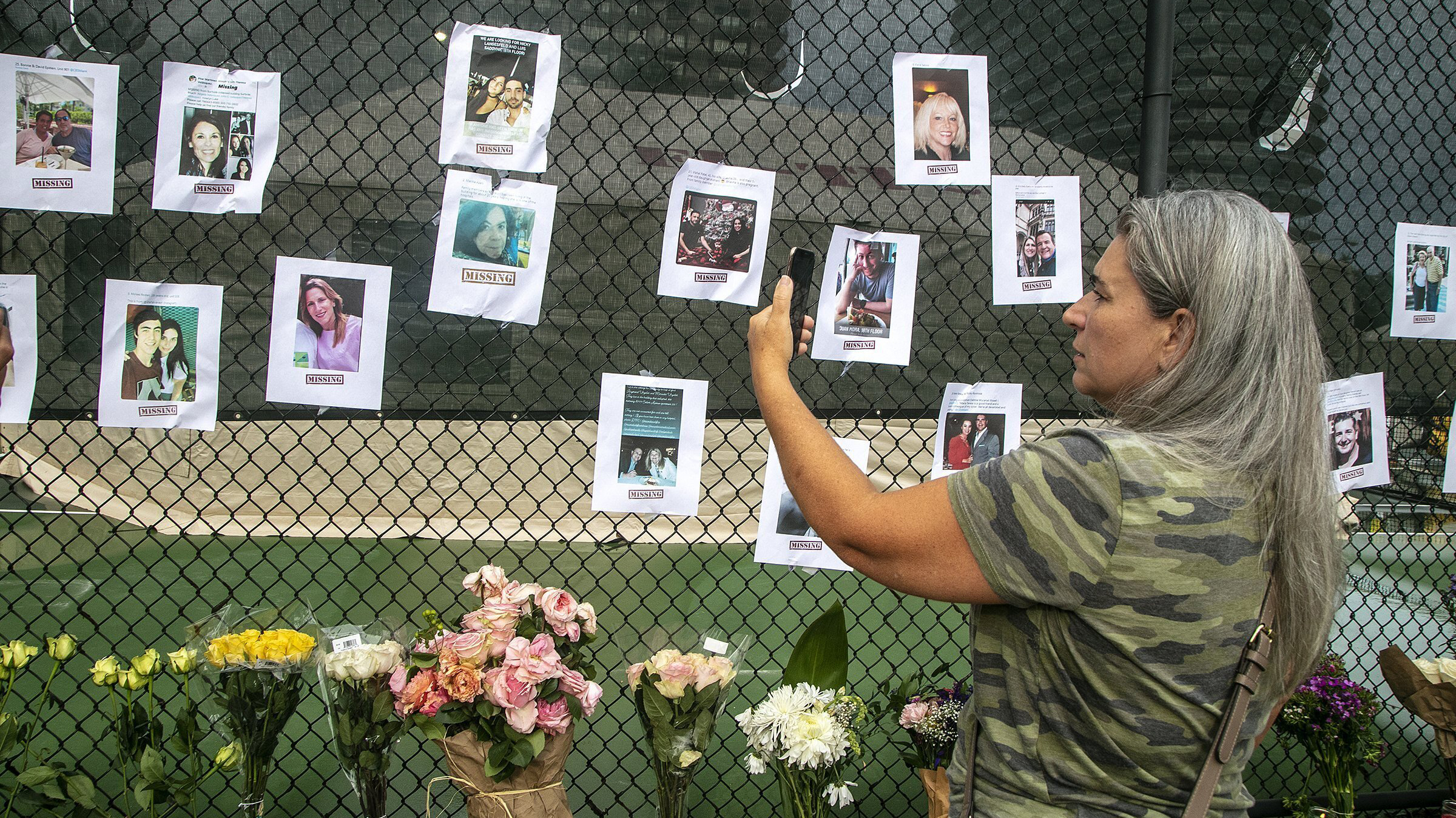 Photos of missing people are posted on a fence near the site of the Champlain Towers South Condo after the building collapsed.