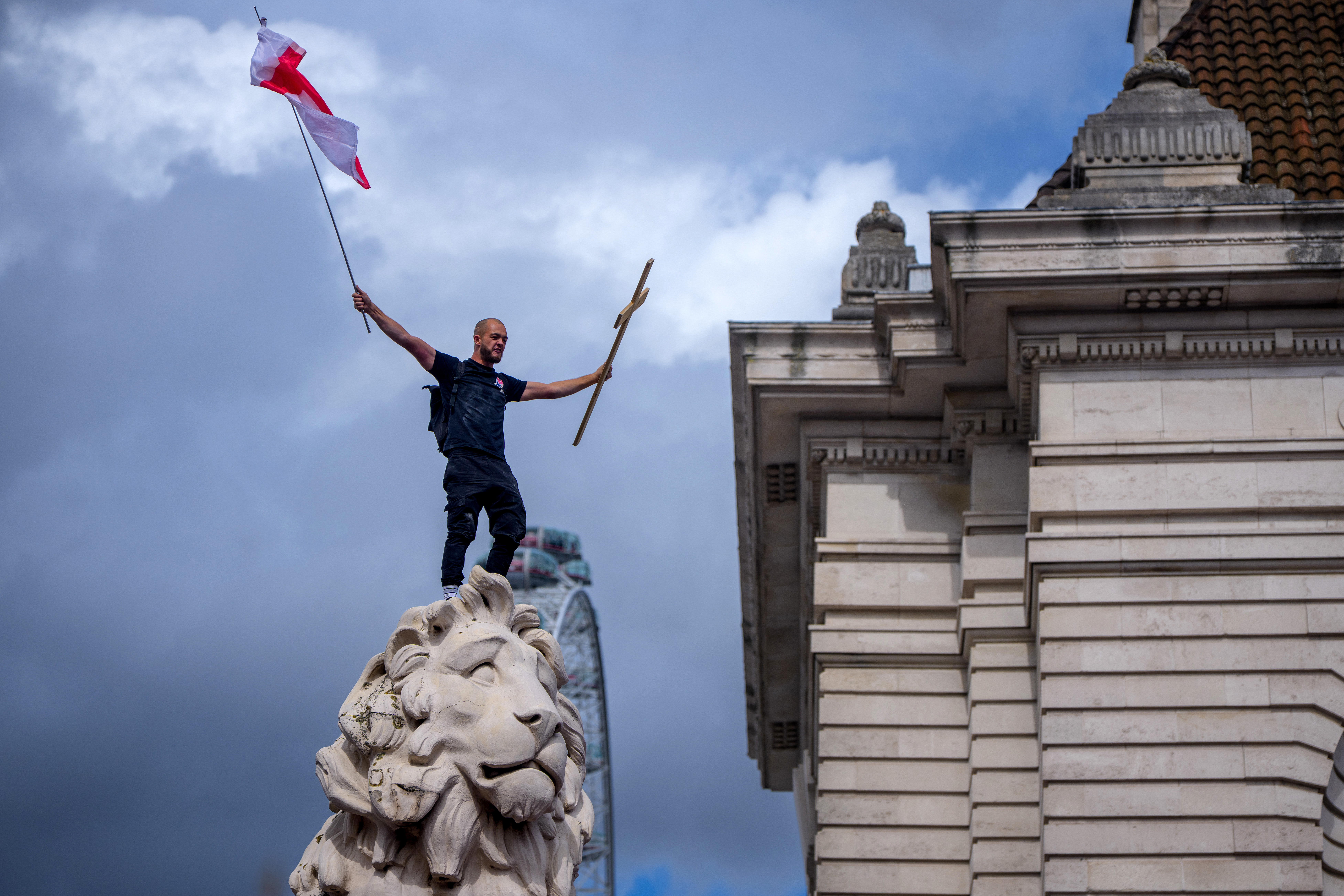 Protesters wave Union Jack and St George's England flags during the "Unite The Kingdom" rally on Westminster Bridge by the Houses of Parliament on September 13, 2025 in London, England.