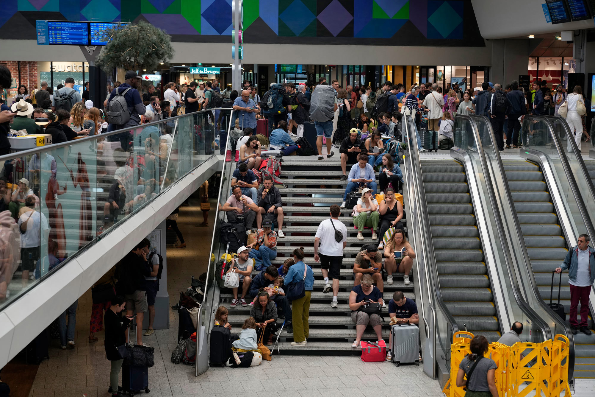 Travellers sit on stairs at the Gare de Montparnasse, at the 2024 Summer Olympics, Friday, July 26, 2024, in Paris, France. 