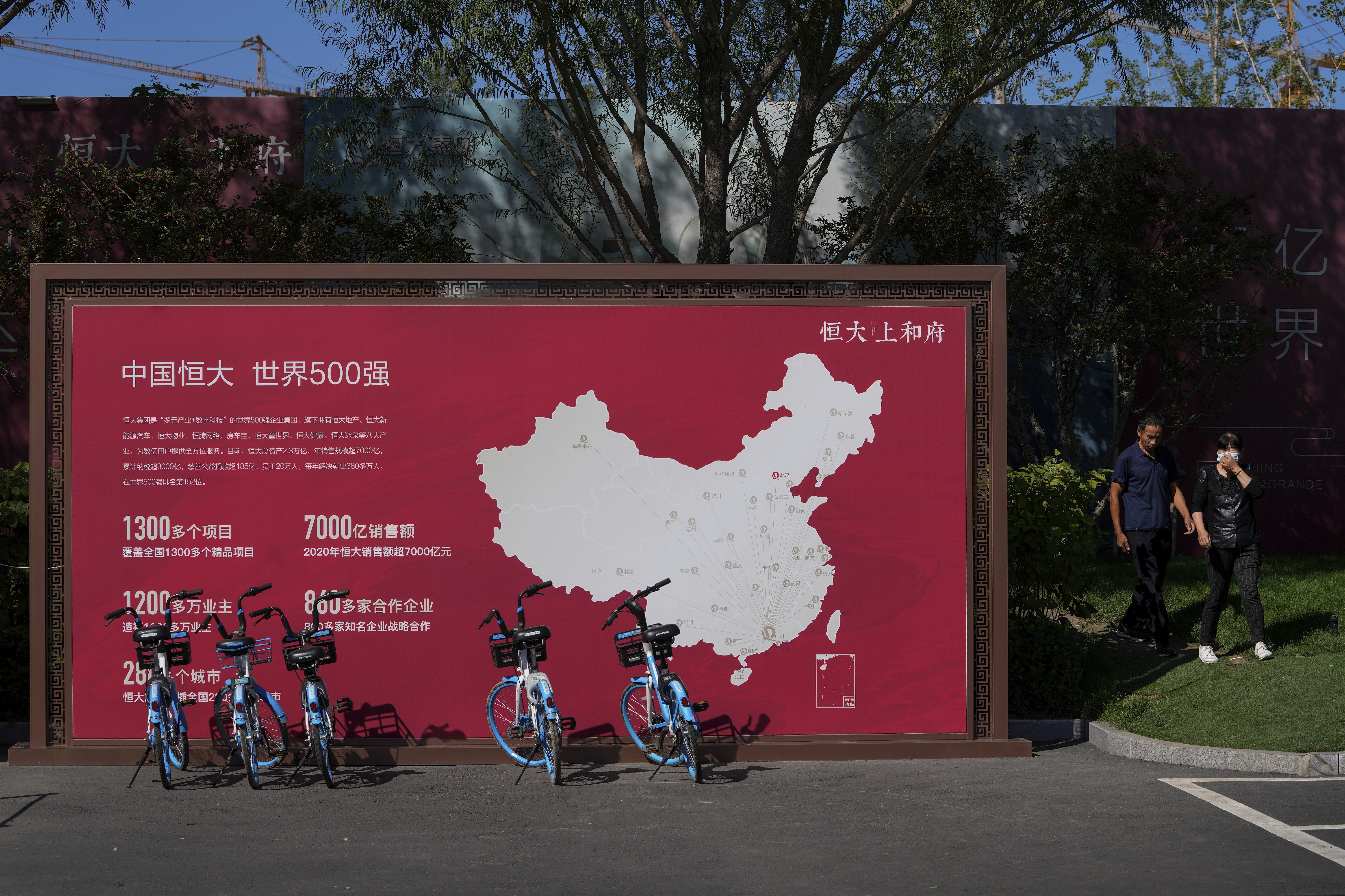 People walk by a map showing Evergrande development projects in China at an Evergrande new housing development in Beijing in September.