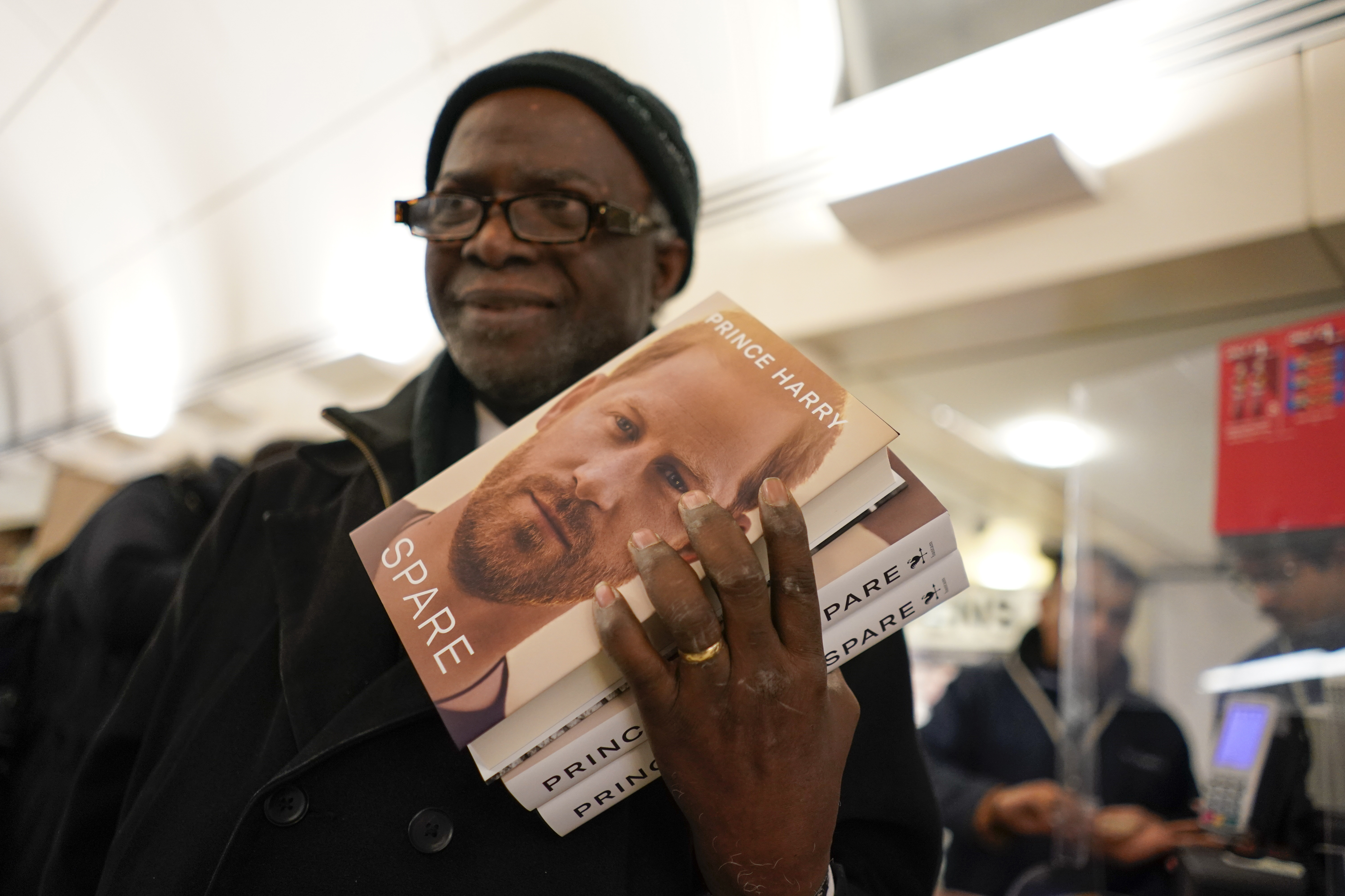 A customer holds copies of the new book by Prince Harry called "Spare" at a book store during a midnight opening in London, Tuesday, Jan. 10, 2023.